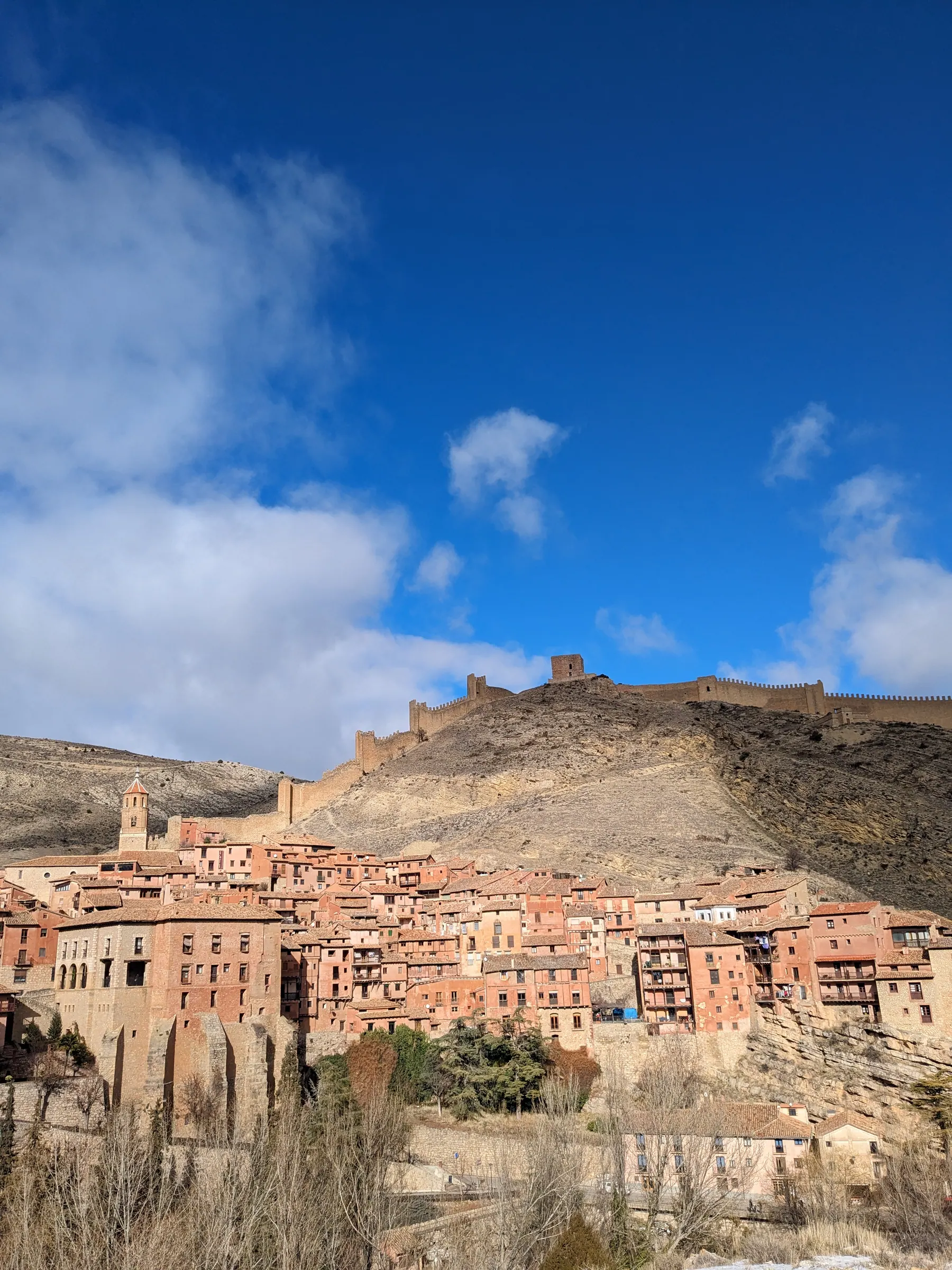 Medieval stone fortress walls and square towers climbing the bare rocky ridge above the houses of Albarracín