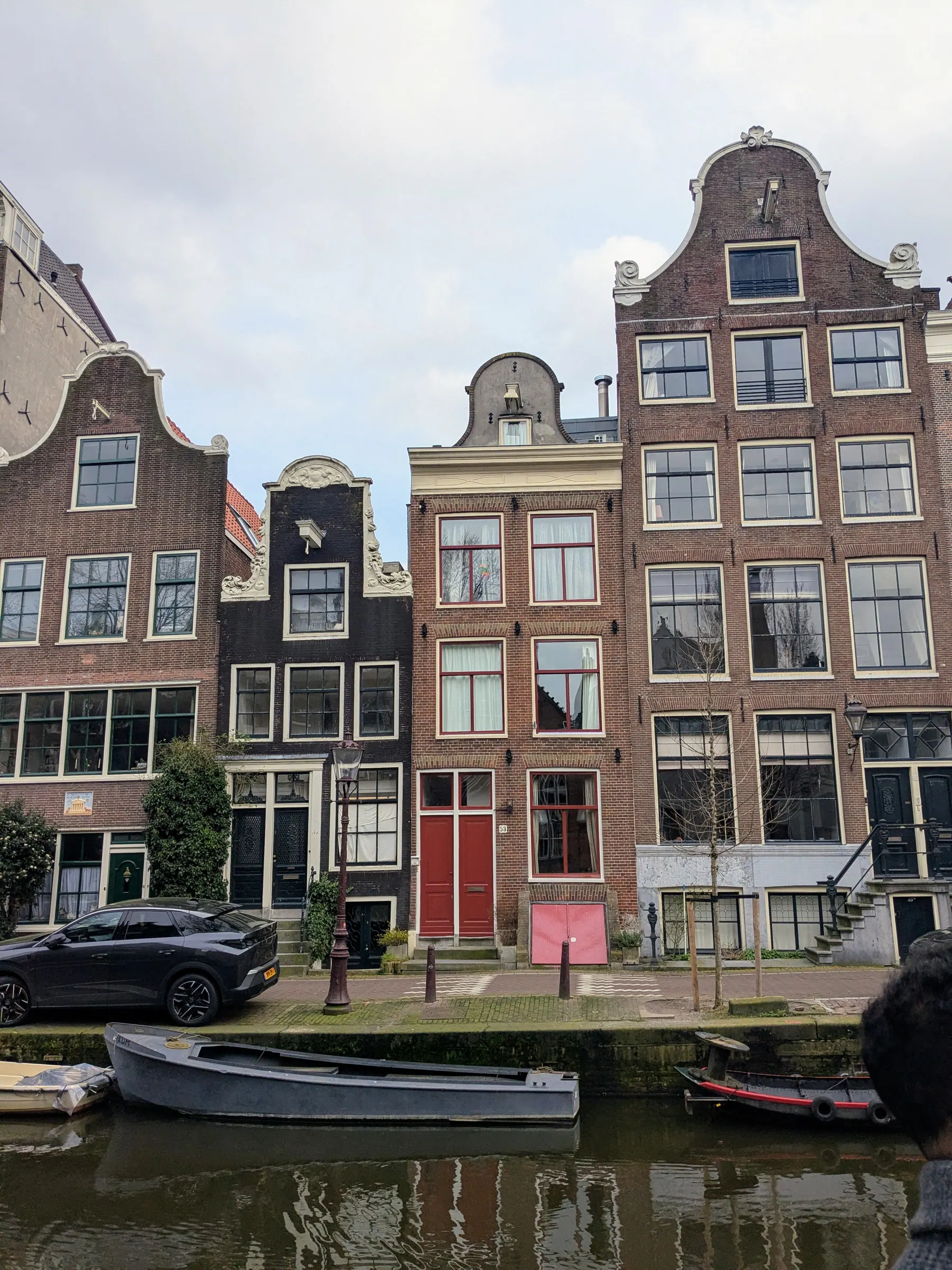 Narrow leaning Amsterdam canal houses with small boats in front