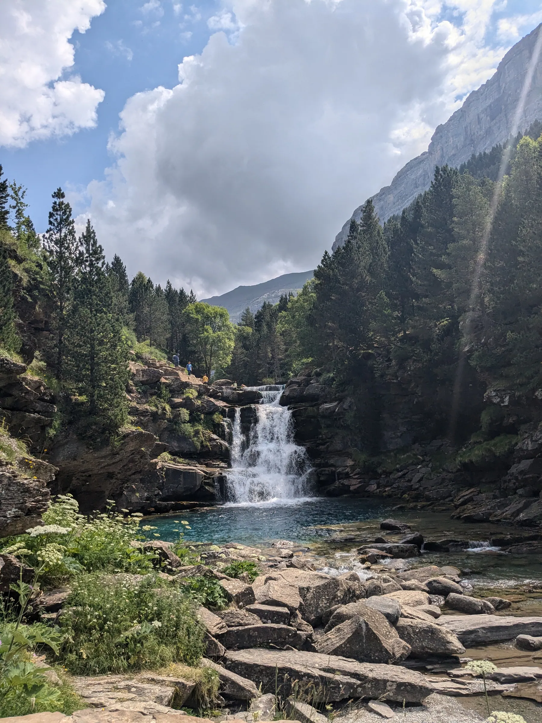 A waterfall flowing through a forested mountain valley in Ordesa