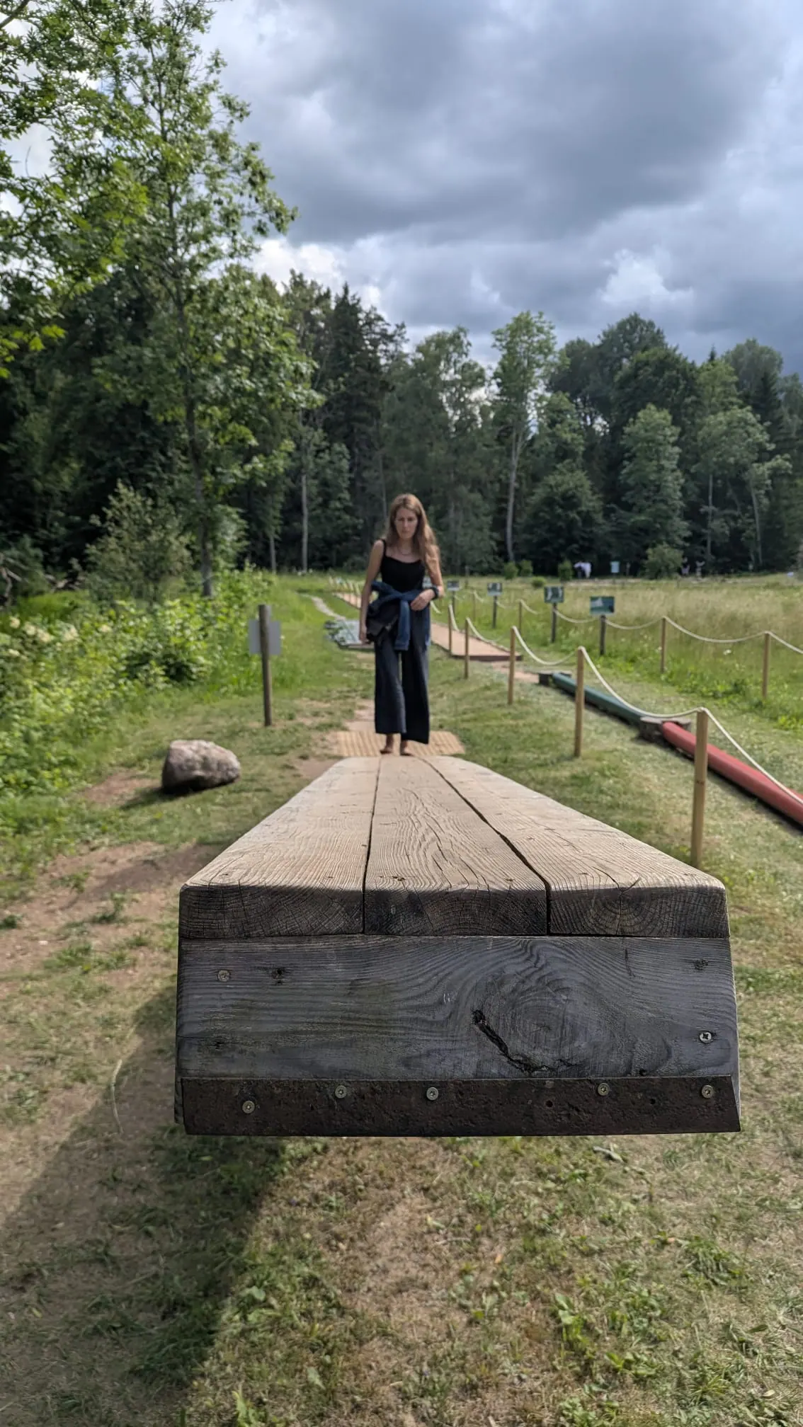 A visitor balancing barefoot on a wooden section of the trail