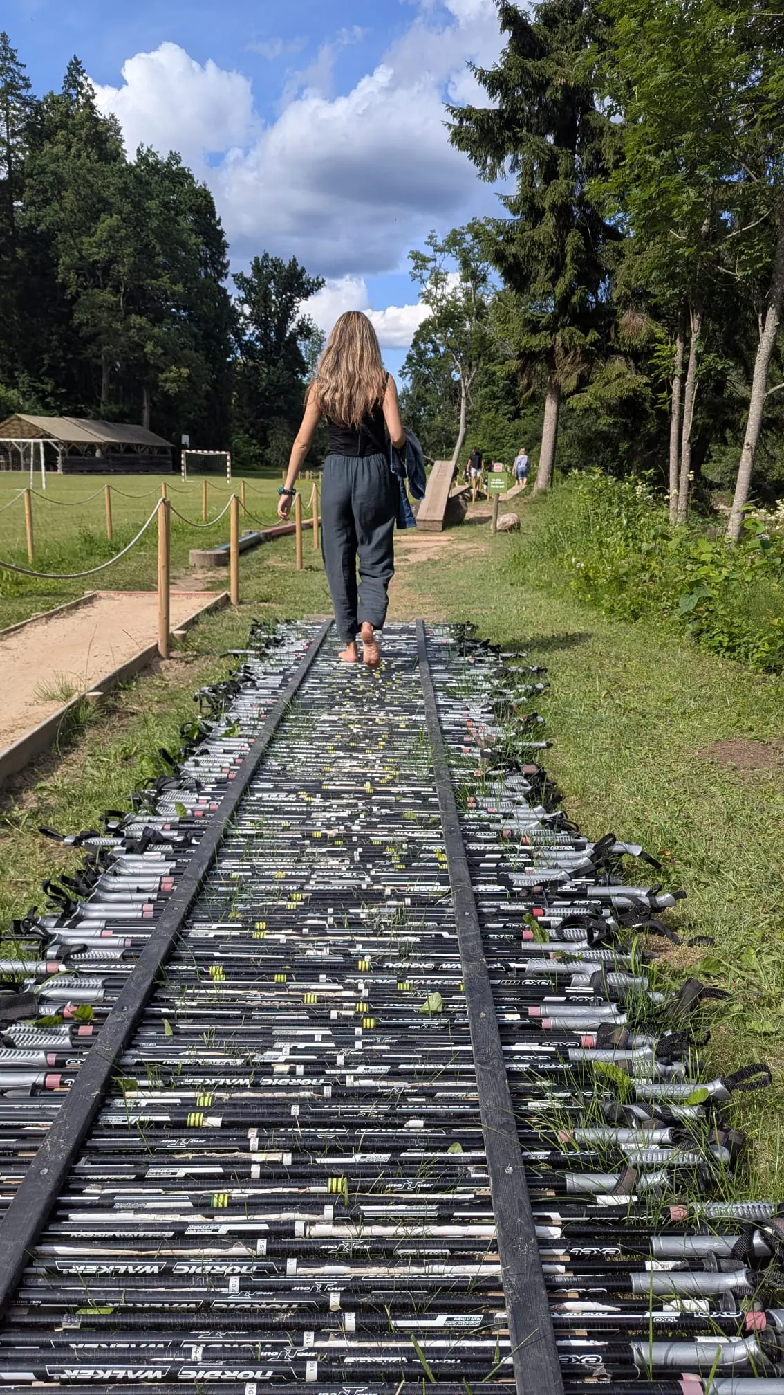 A visitor walking barefoot across a path made from old ski poles