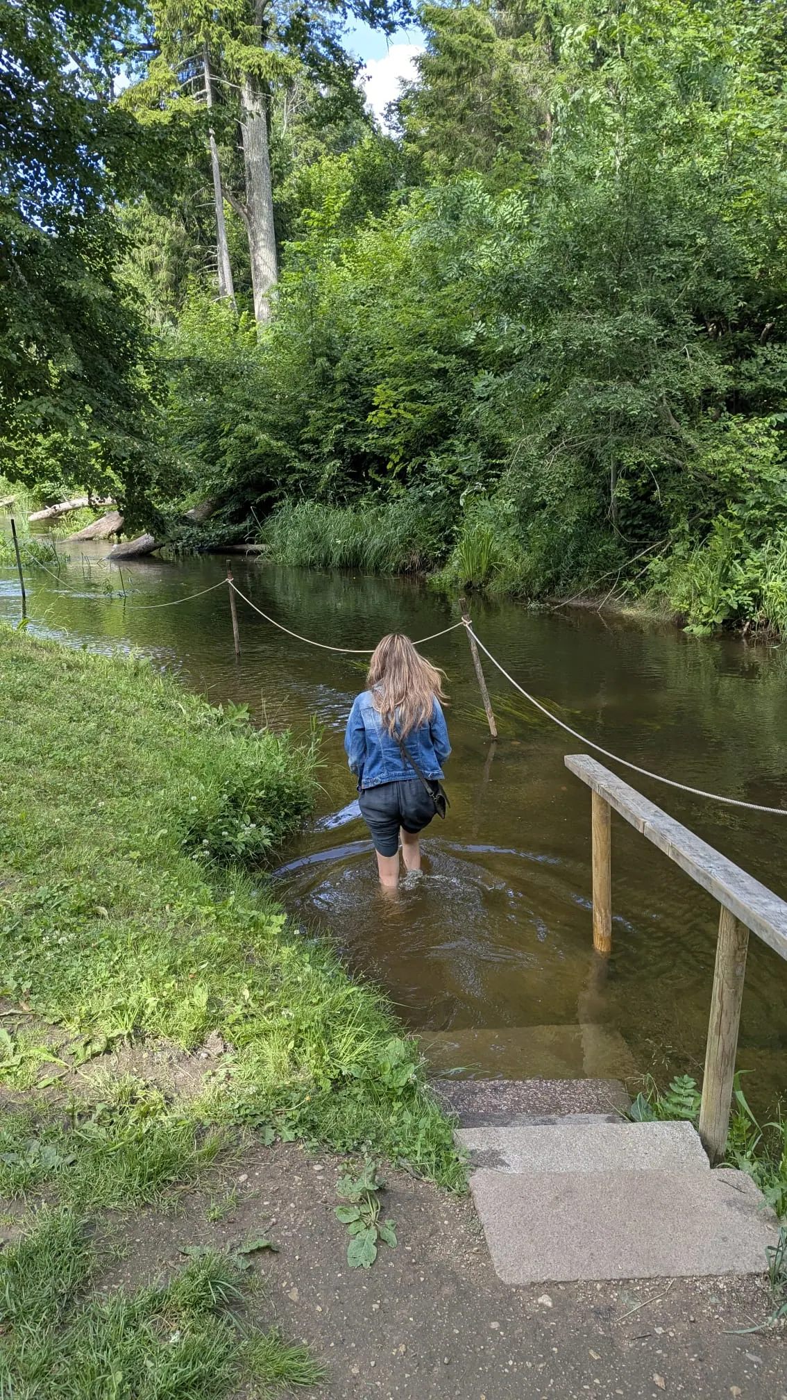 A visitor wading barefoot through the river crossing