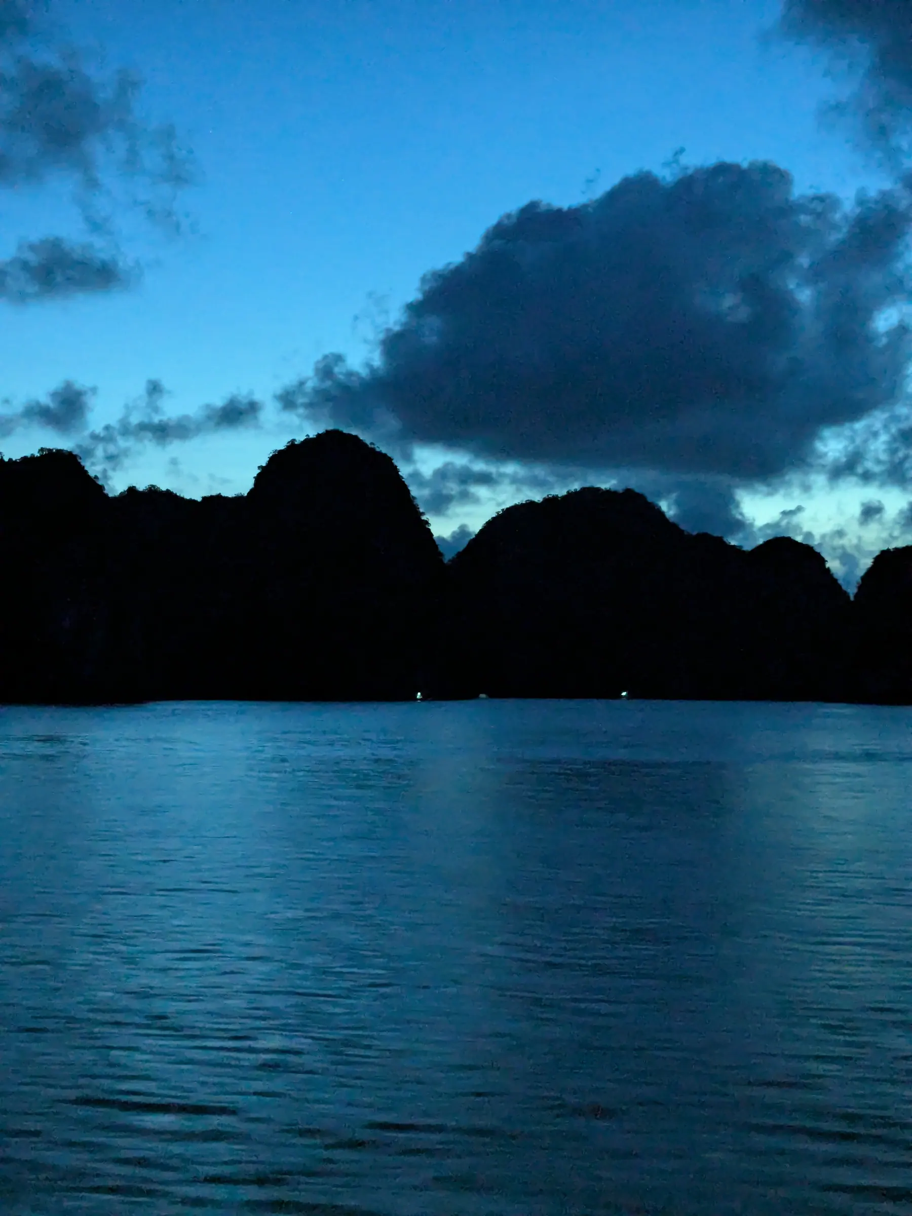 Twilight skies deepening to blue over silent limestone islands in Lan Ha Bay