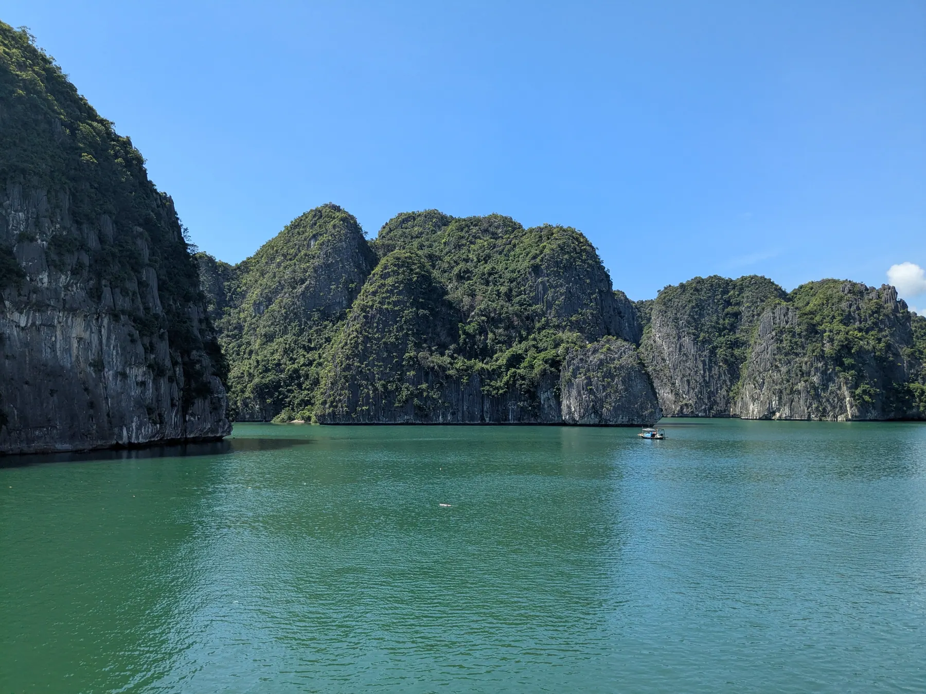Sheer vertical limestone karst islands rising out of calm turquoise water under bright sunshine