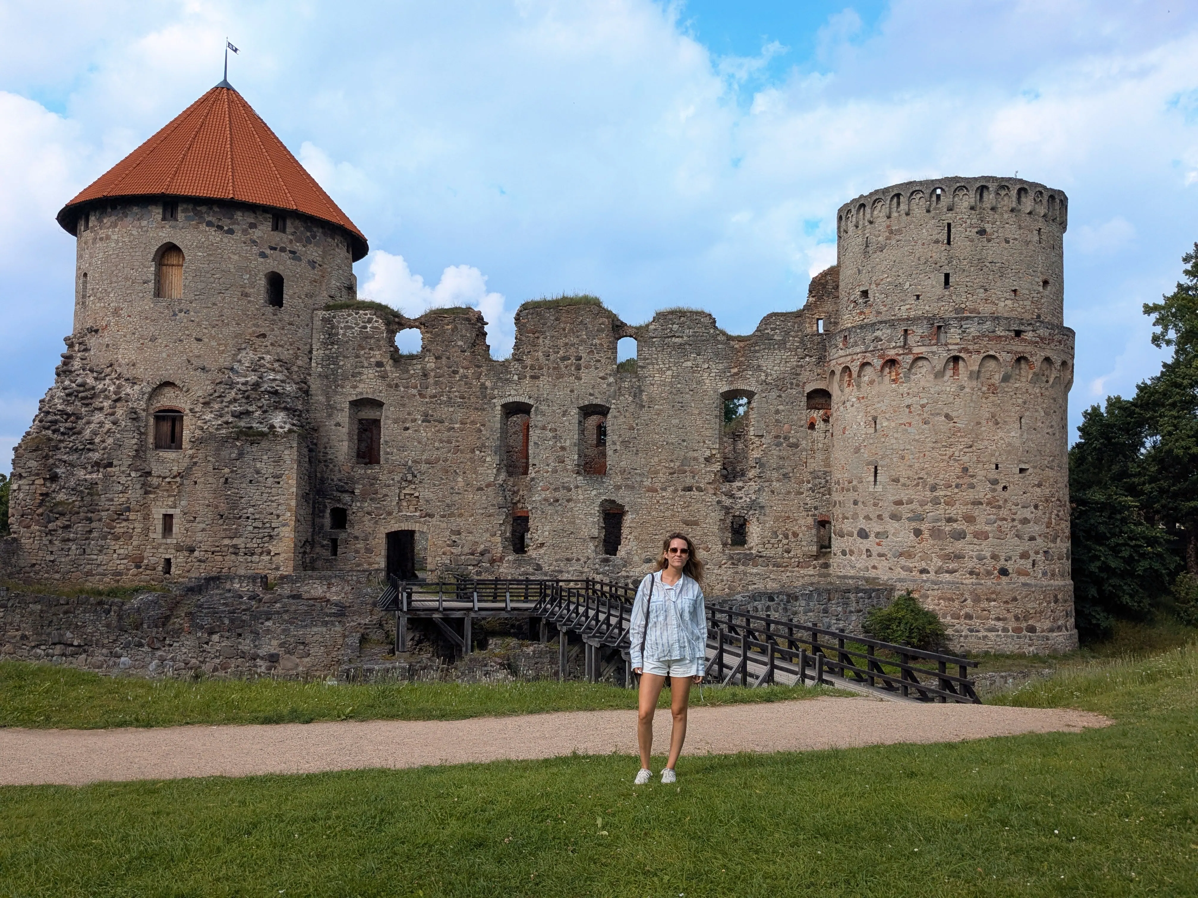 The imposing stone ruins and round defense tower of medieval Cēsis Castle surrounded by lush parkland lawns