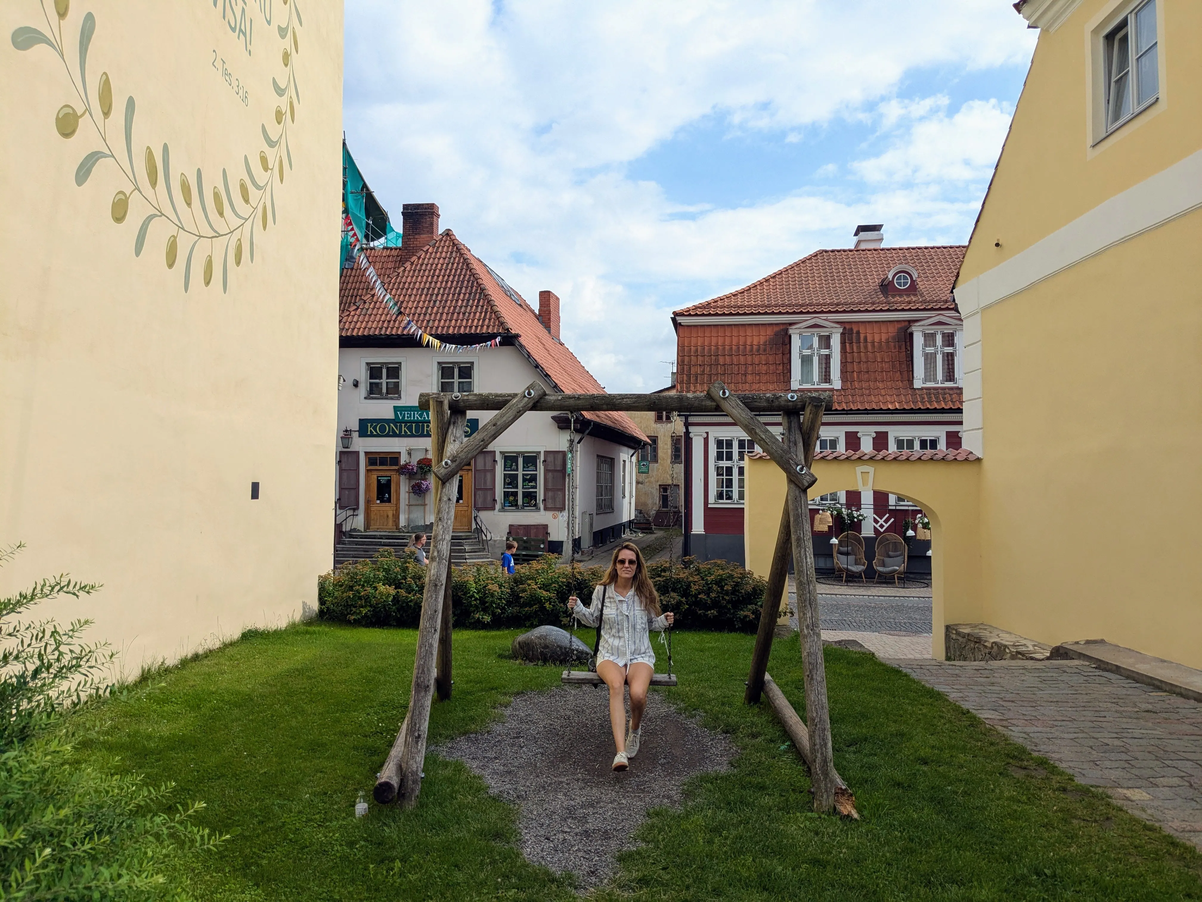 Historic brick and pastel facades framing the pedestrian cobblestone square of Rose Square in Cēsis Old Town