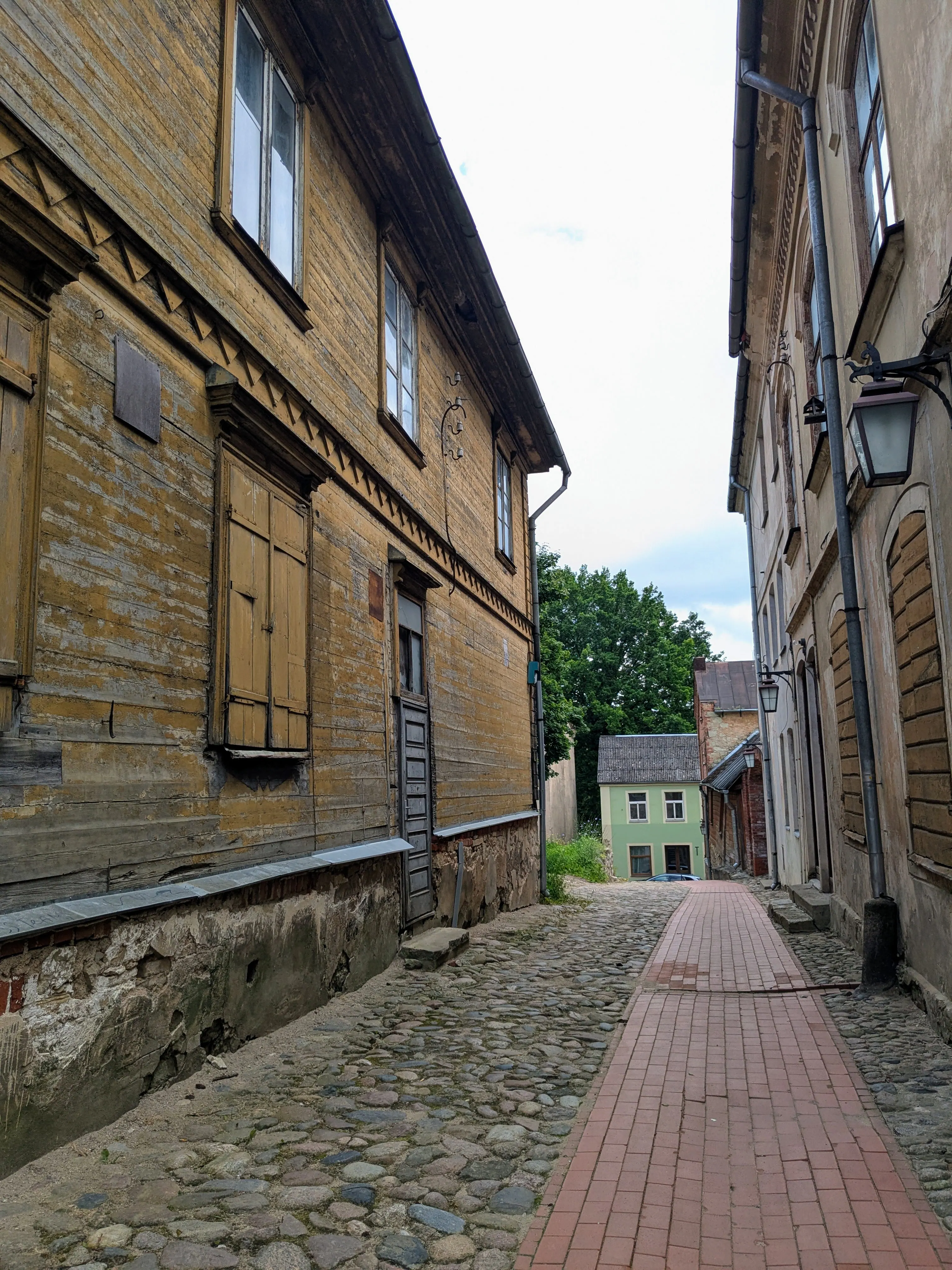 A cobbled lane beside an old timber building in Cēsis