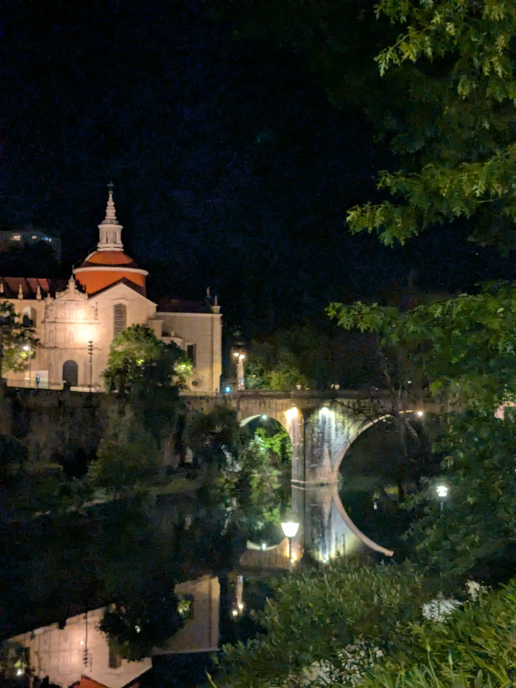 A church and old stone bridge reflected in the river at night in Amarante