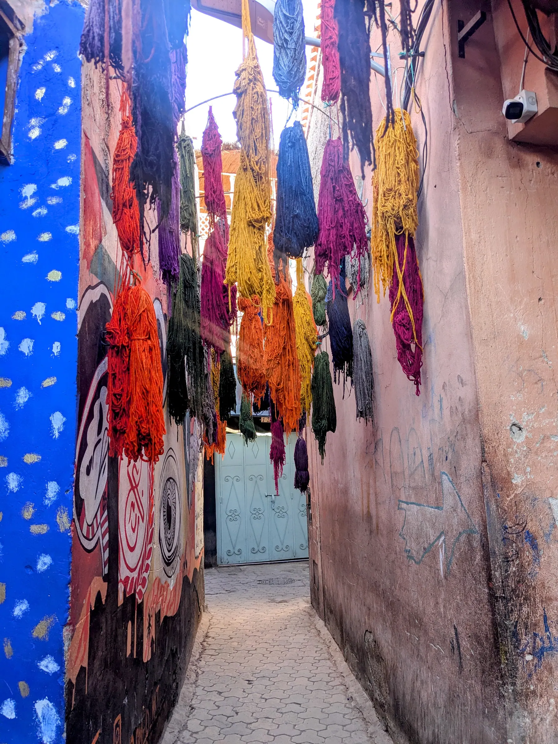 A colorful narrow alley in the Essaouira medina with hanging textiles