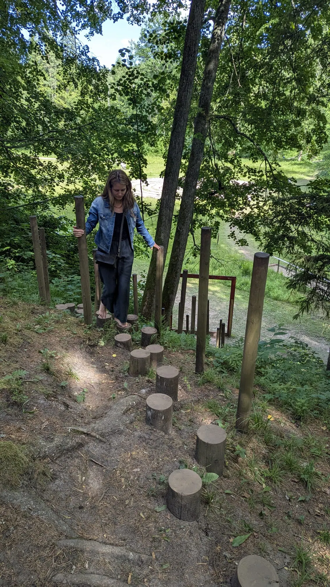 A visitor stepping across wooden stumps at Valguma Pasaule