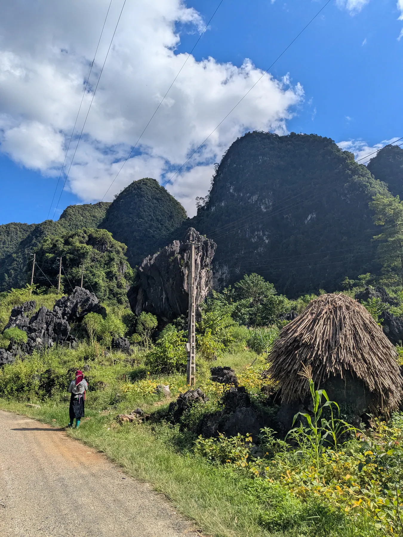 Motorbike on a narrow lane beside a haystack and limestone peaks near Lung Ho