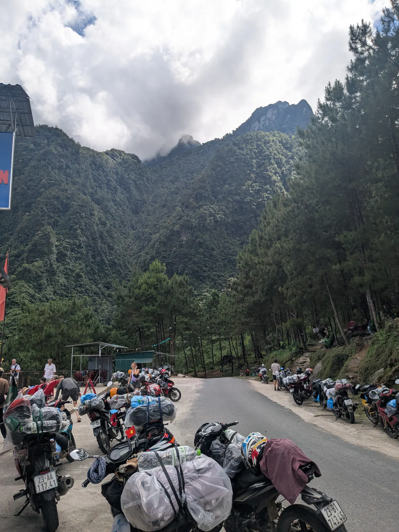 Touring motorbikes with luggage gathered beside a bend below limestone cliffs near Lung Tam