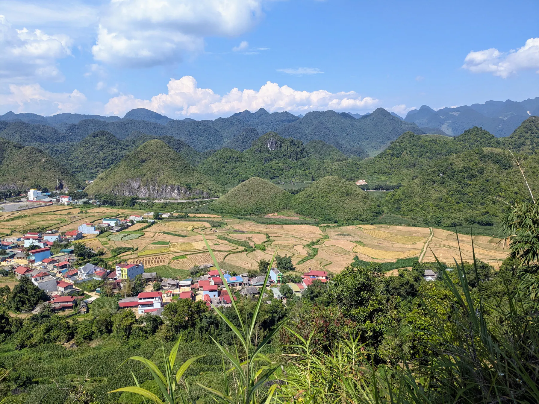 The rounded Twin Mountains rising behind fields and village rooftops in Quan Ba