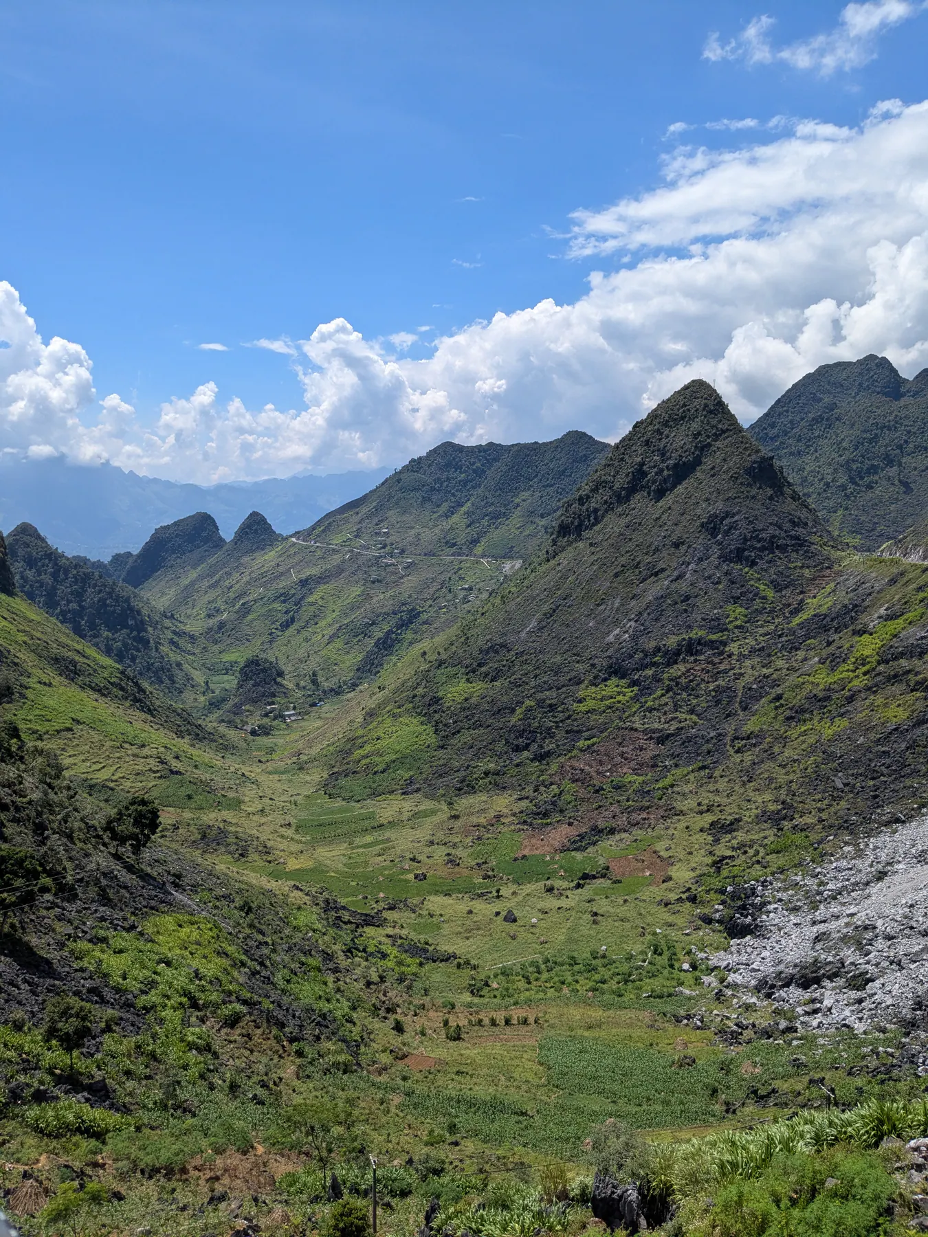 A road cut across the foot of sharp green limestone ridges around Lung Phin