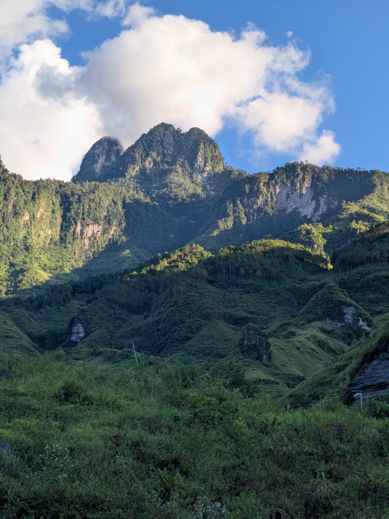 Sunlit limestone peaks above a green valley viewed from the Du Gia homestay area