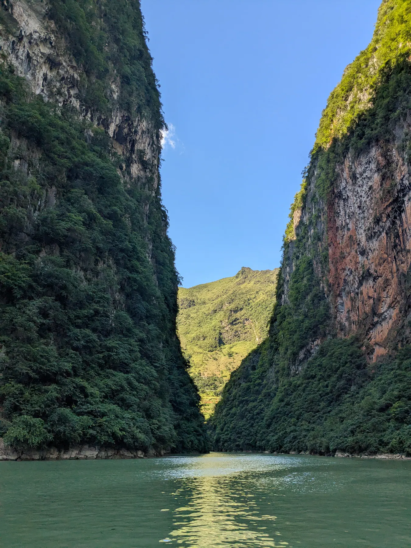 Sheer rock walls rising from green water on both sides of the narrow Tu San canyon