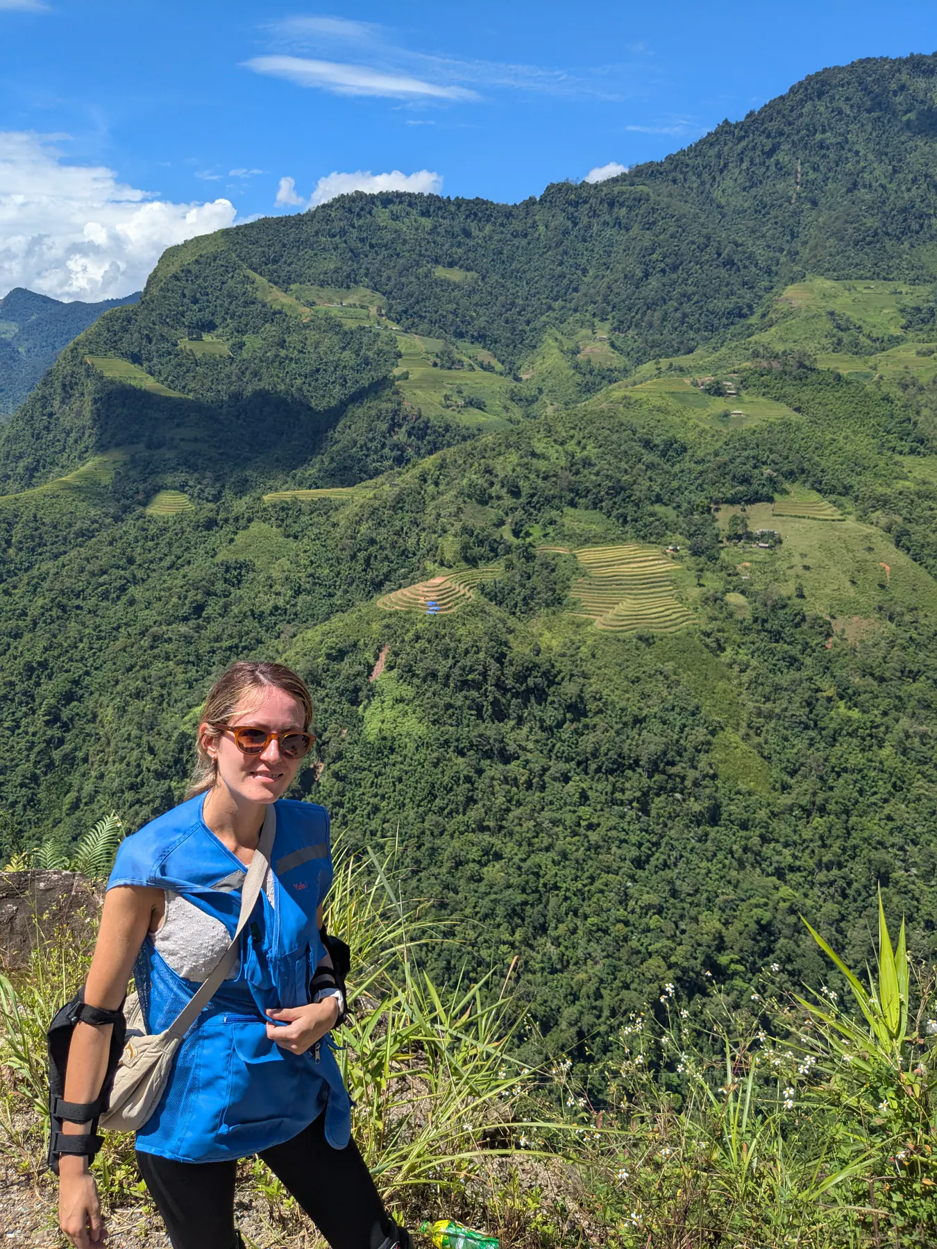 A traveller with protective elbow pads beside steep green slopes on the first day of the Ha Giang loop