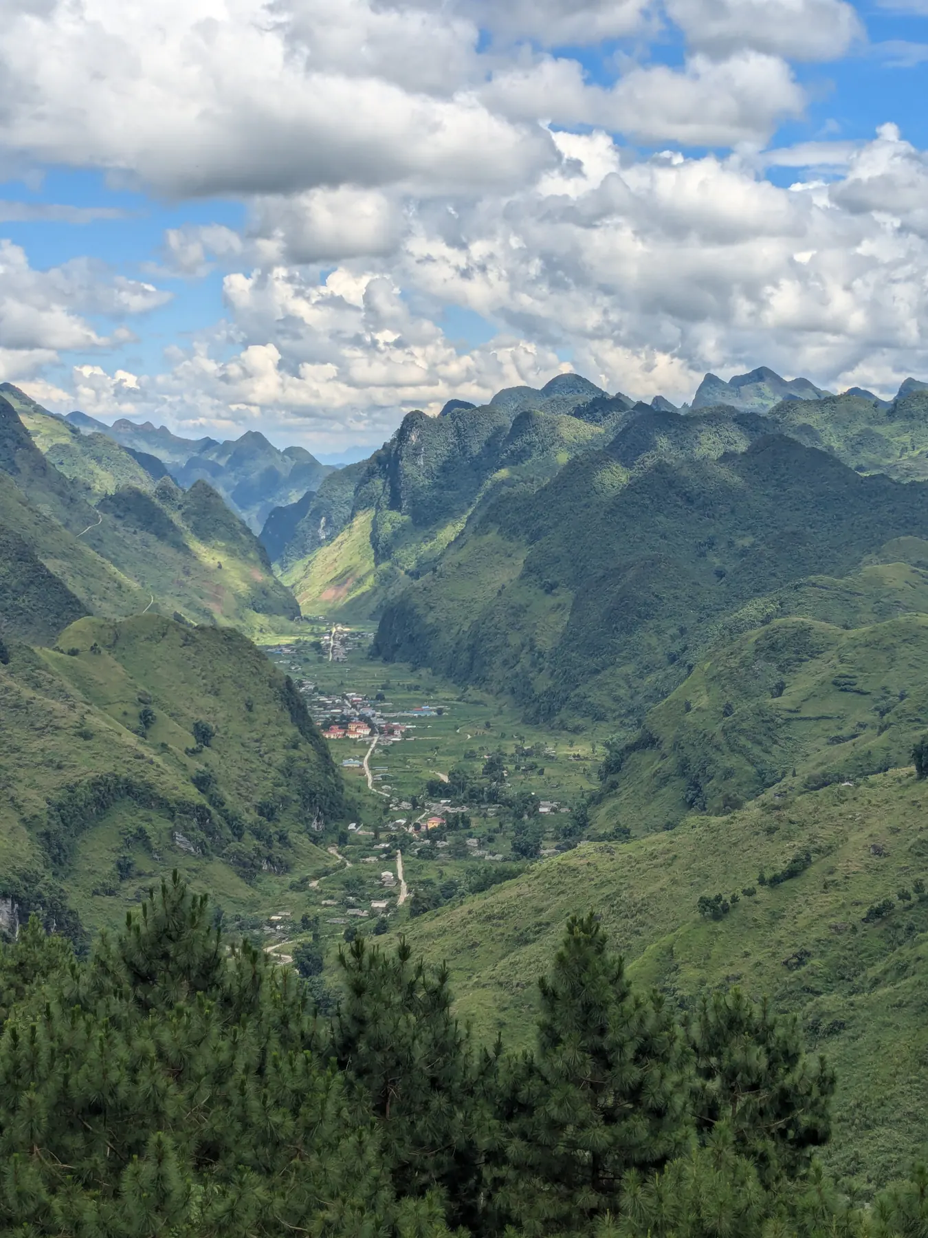 Village buildings and cultivated fields in a deep green valley below the Lung Tam viewpoint