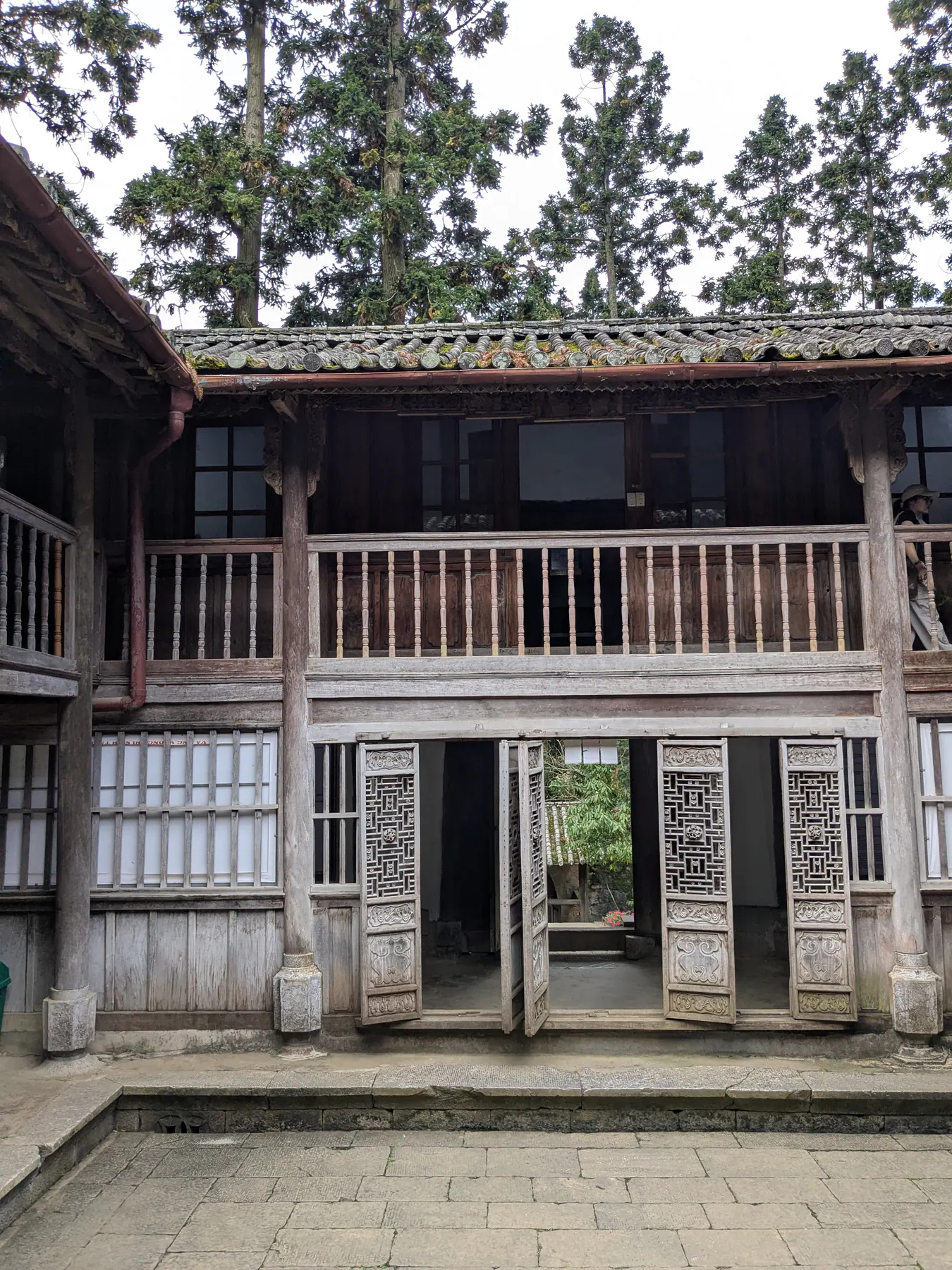 A two-storey timber facade with a balcony facing a stone courtyard in the Hmong King's palace at Sa Phin
