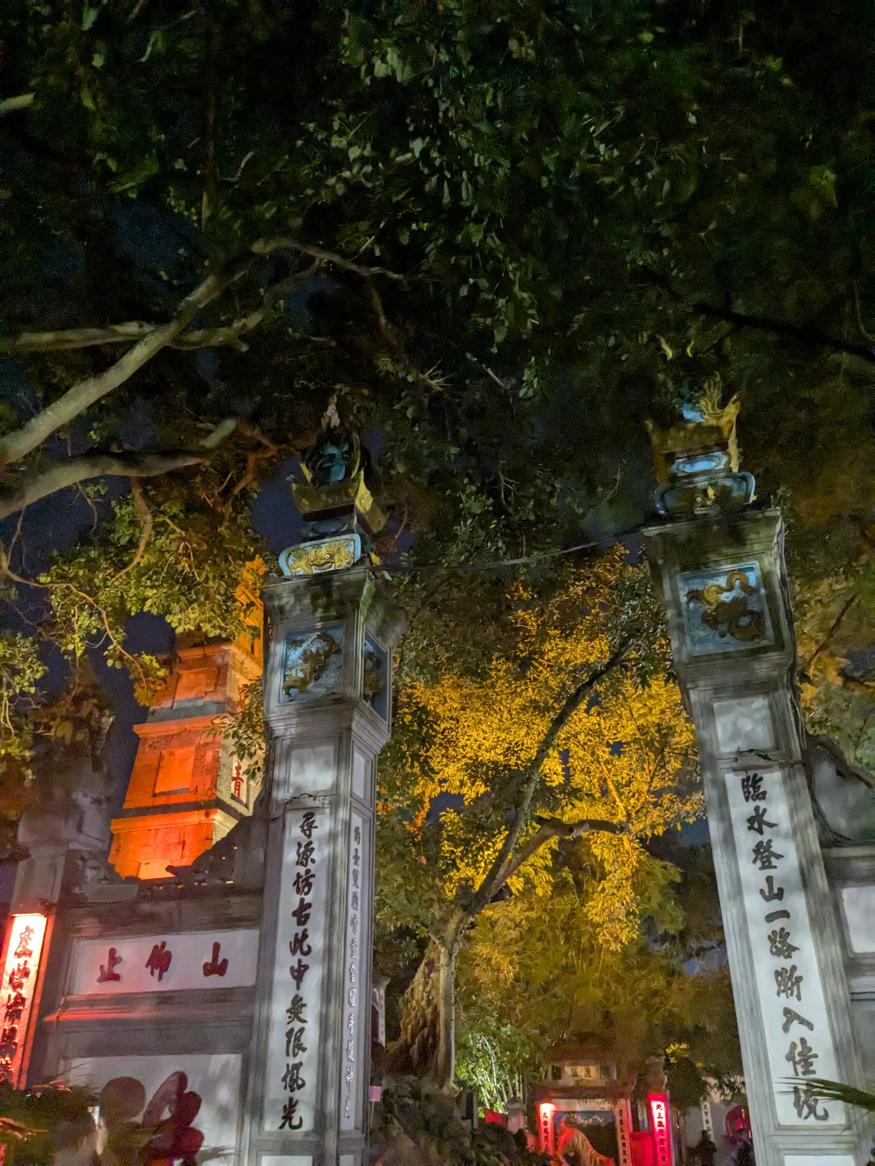 The red Thê Húc Bridge lit at night across Hoan Kiem Lake