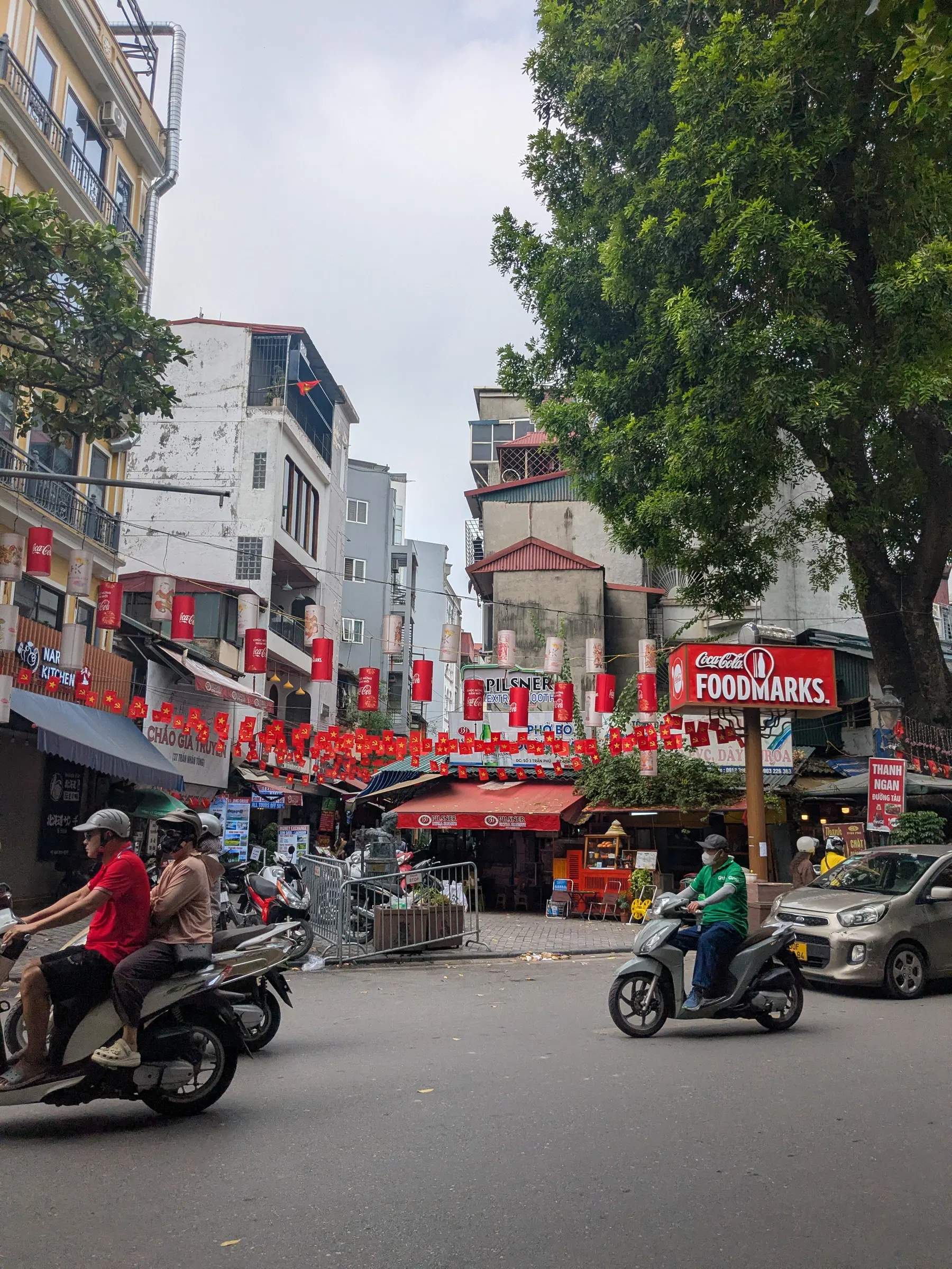 Motorbikes moving through a busy Hanoi street lined with cafés