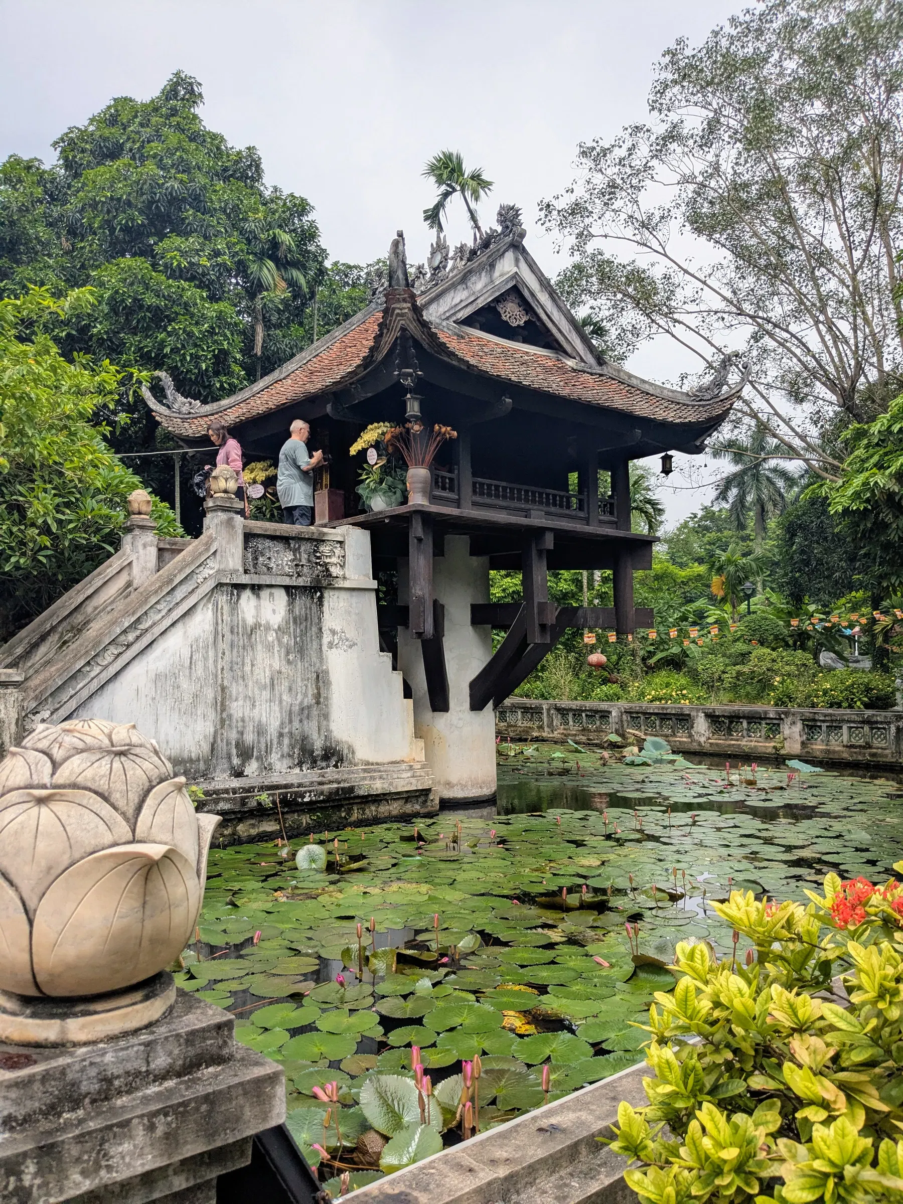 A traditional wooden temple structure beside a lotus pond in Hanoi