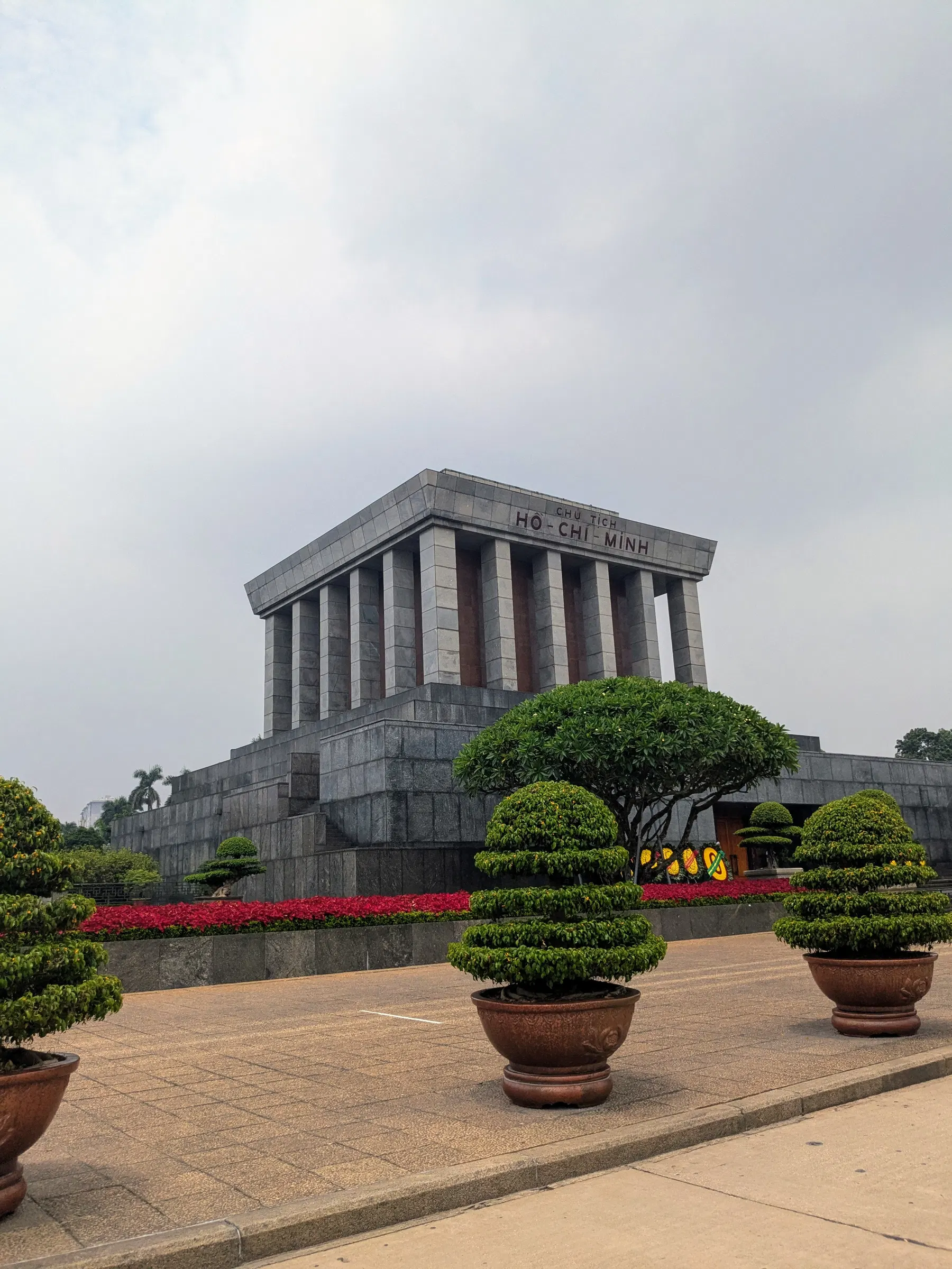 The grey stone Ho Chi Minh Mausoleum behind formal gardens in Hanoi