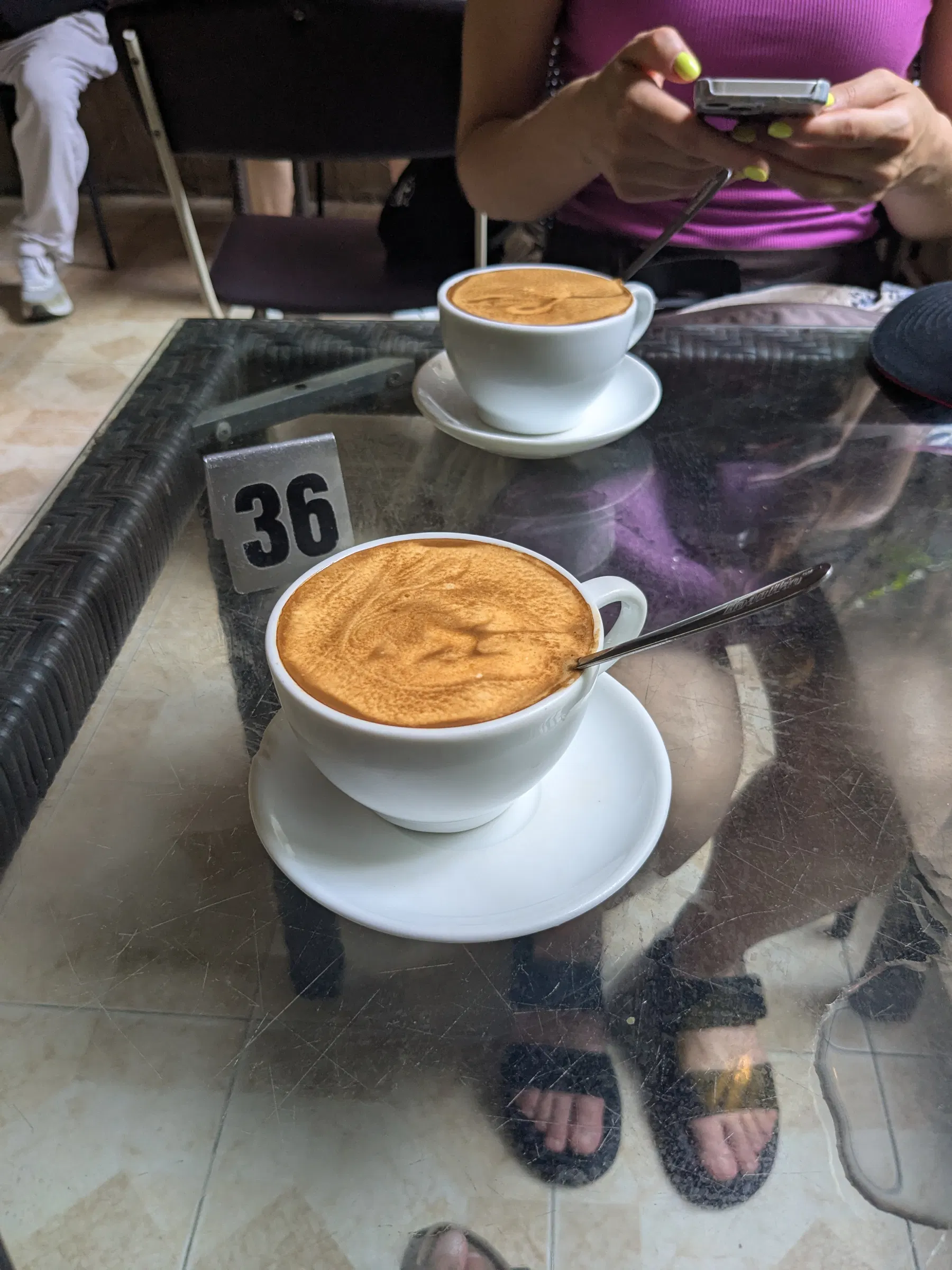 Two cups of egg coffee on a small glass table in Hanoi