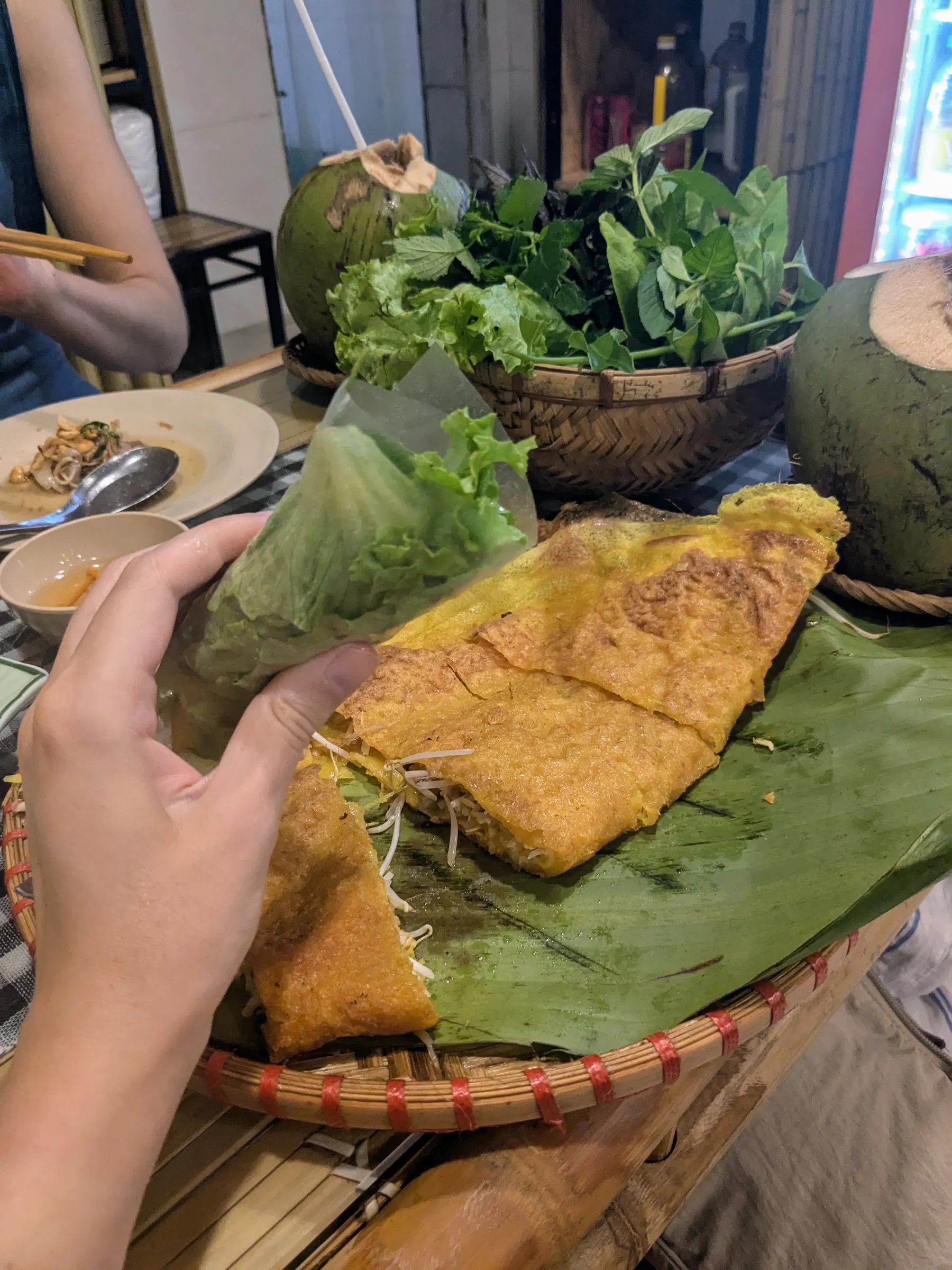 A crisp bánh xèo pancake served with herbs and lettuce in Hanoi