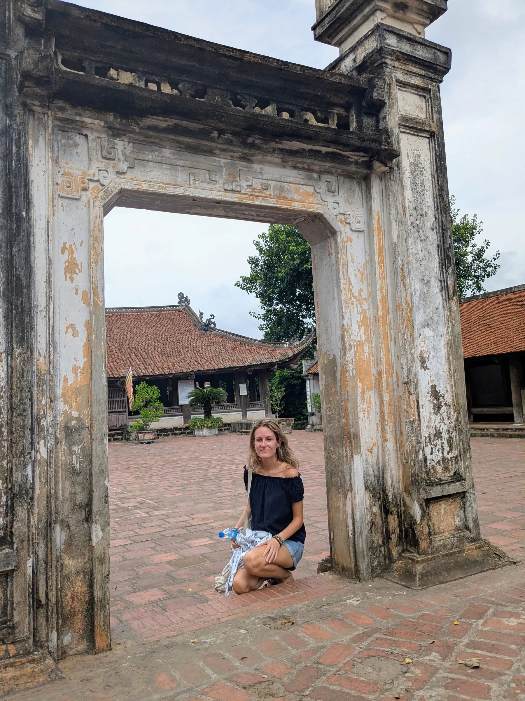 A traveller beneath a weathered stone gateway in Đường Lâm village