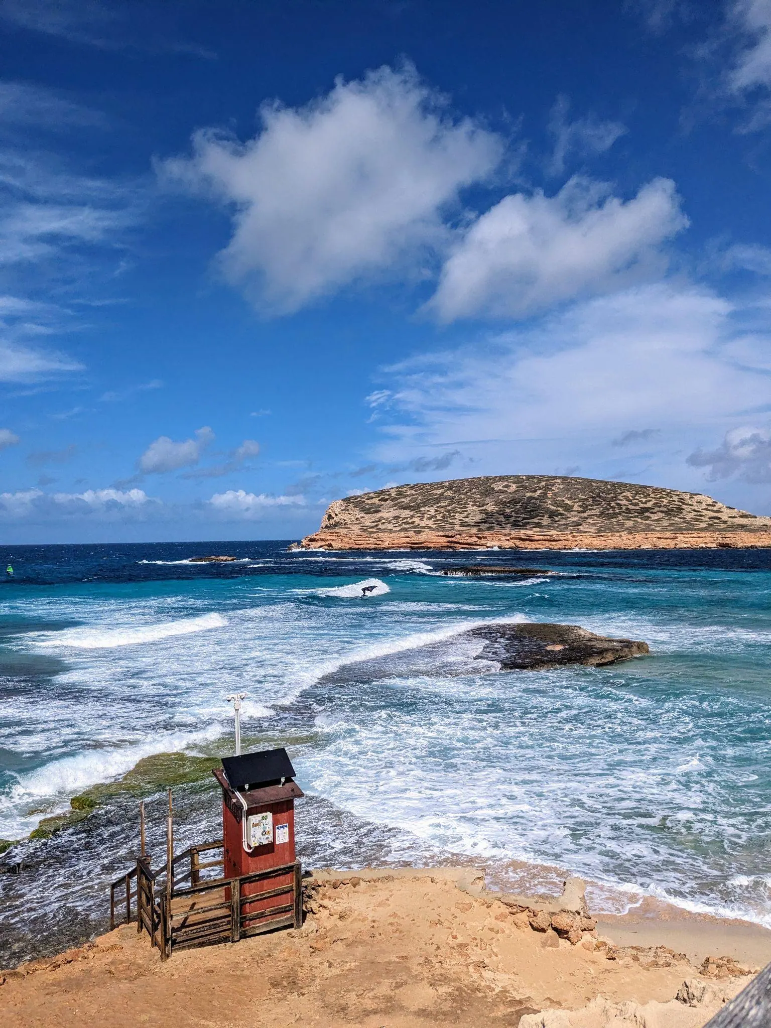 Shallow crystalline water and offshore rocky islets at Platges de Comte