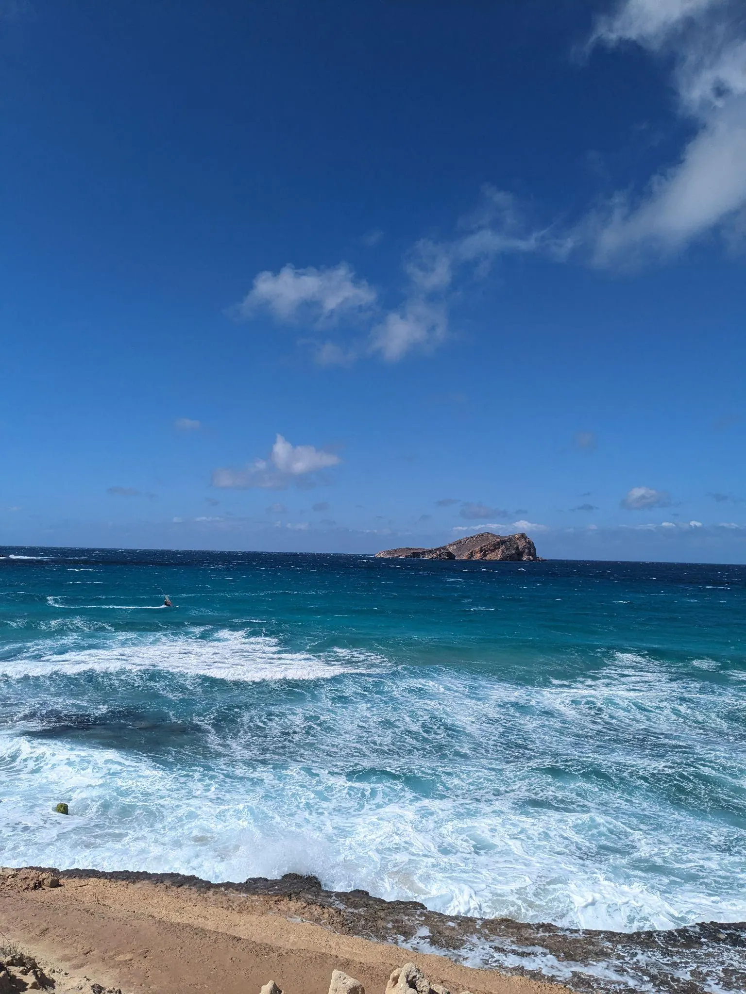 Rocky shoreline and open sea views toward offshore islets along the coastal trail