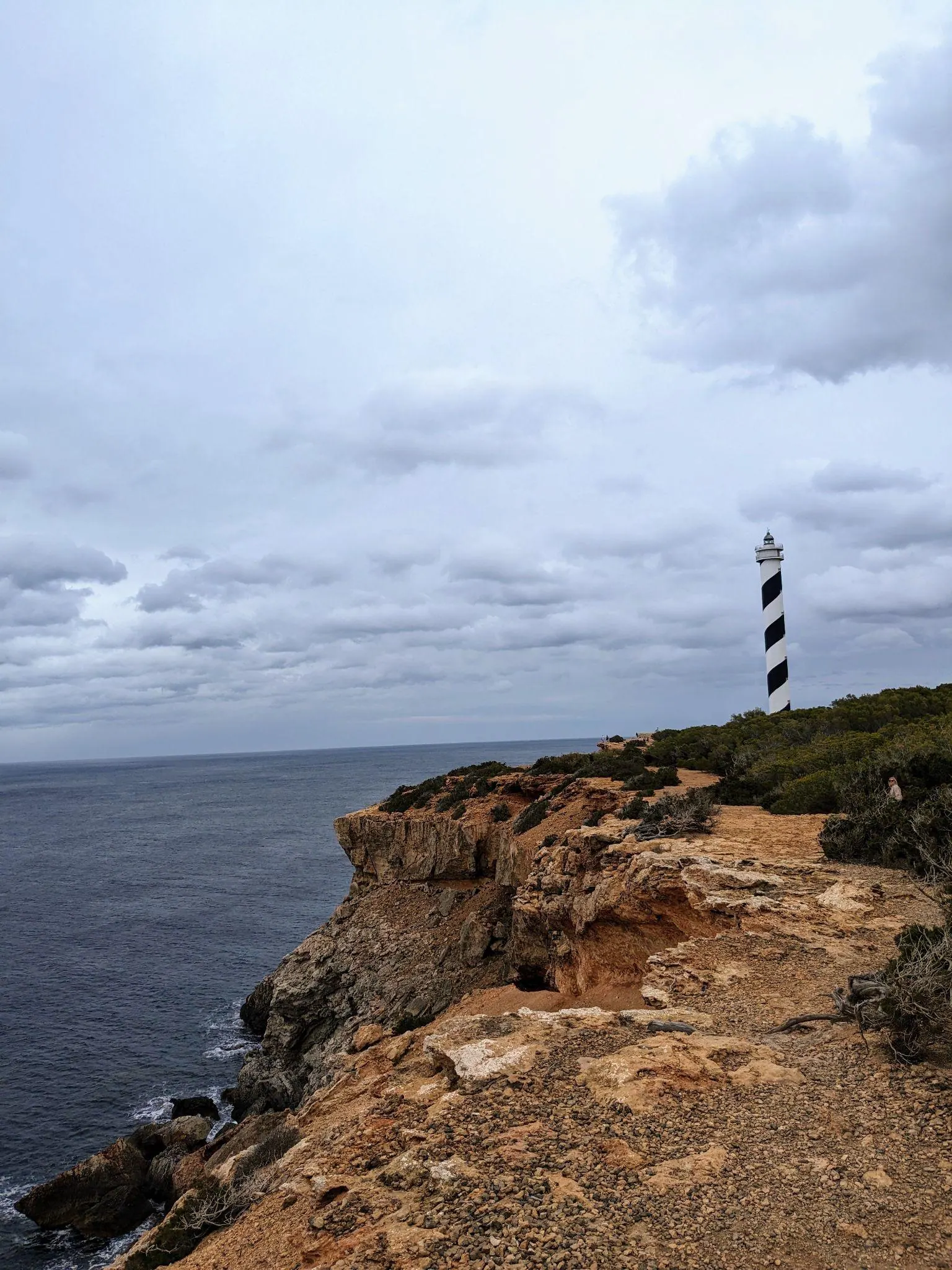 Narrow dirt walking trail along rocky cliff tops near Portinatx