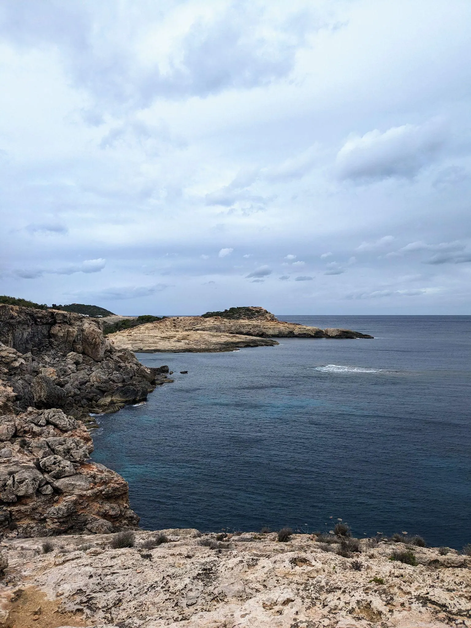 The tall black and white spiral Far de sa Punta des Moscarter on the coastal edge