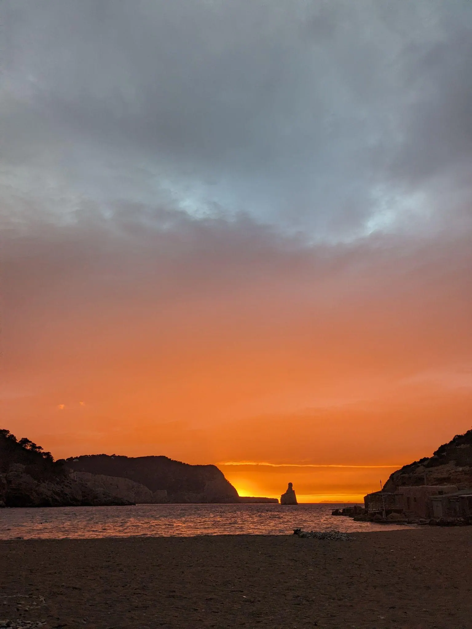The iconic pointed silhouette of Cap Bernat rock in Cala Benirràs under an evening sky