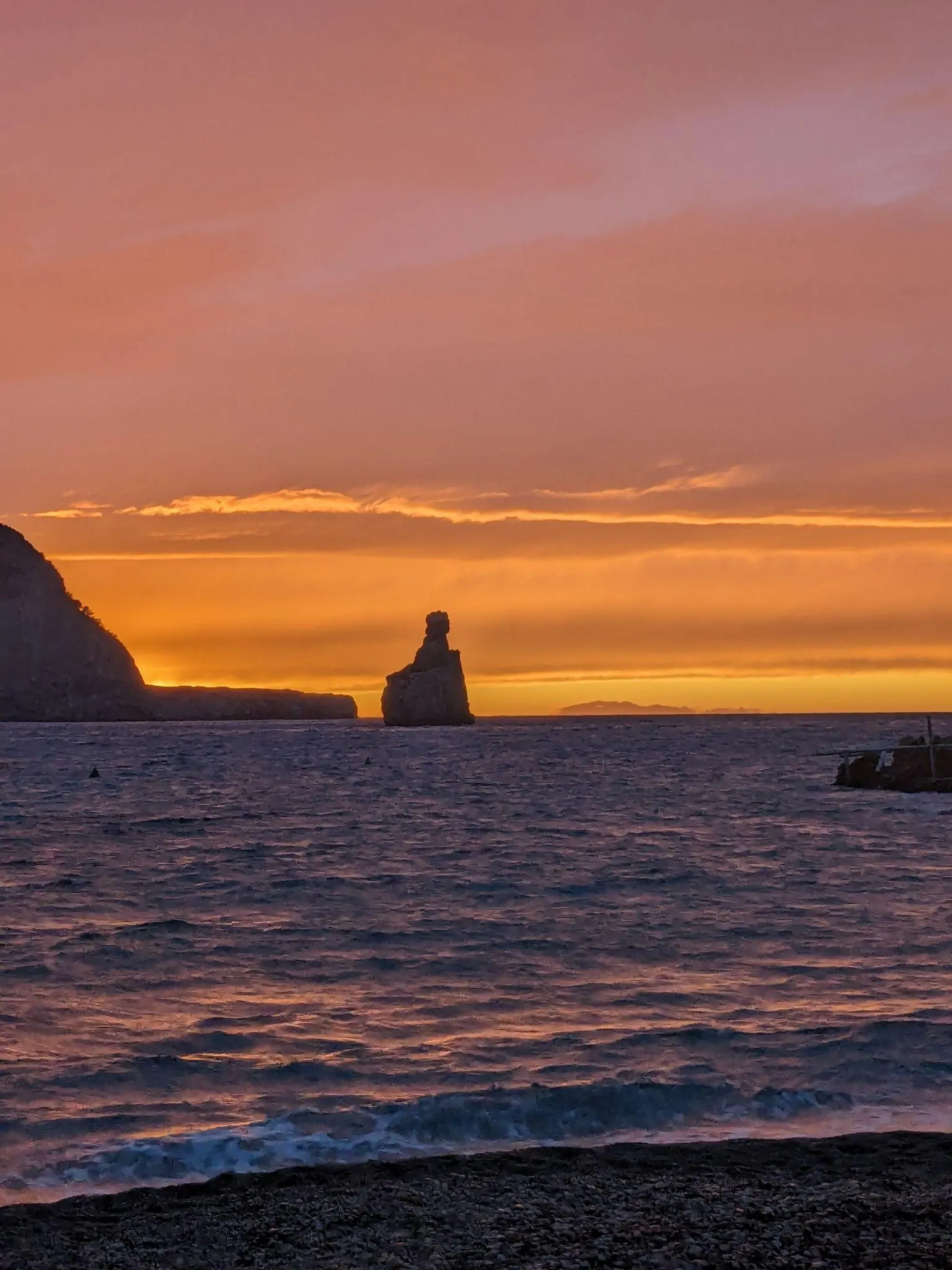 Sunset over the Mediterranean Sea framing the prominent silhouette of Cap Bernat sea stack at Cala Benirràs