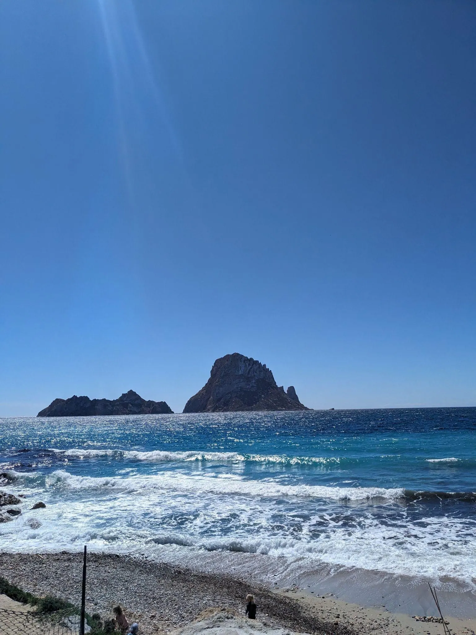 Cala d'Hort beach with sandy shore and coastal restaurants facing Es Vedrà