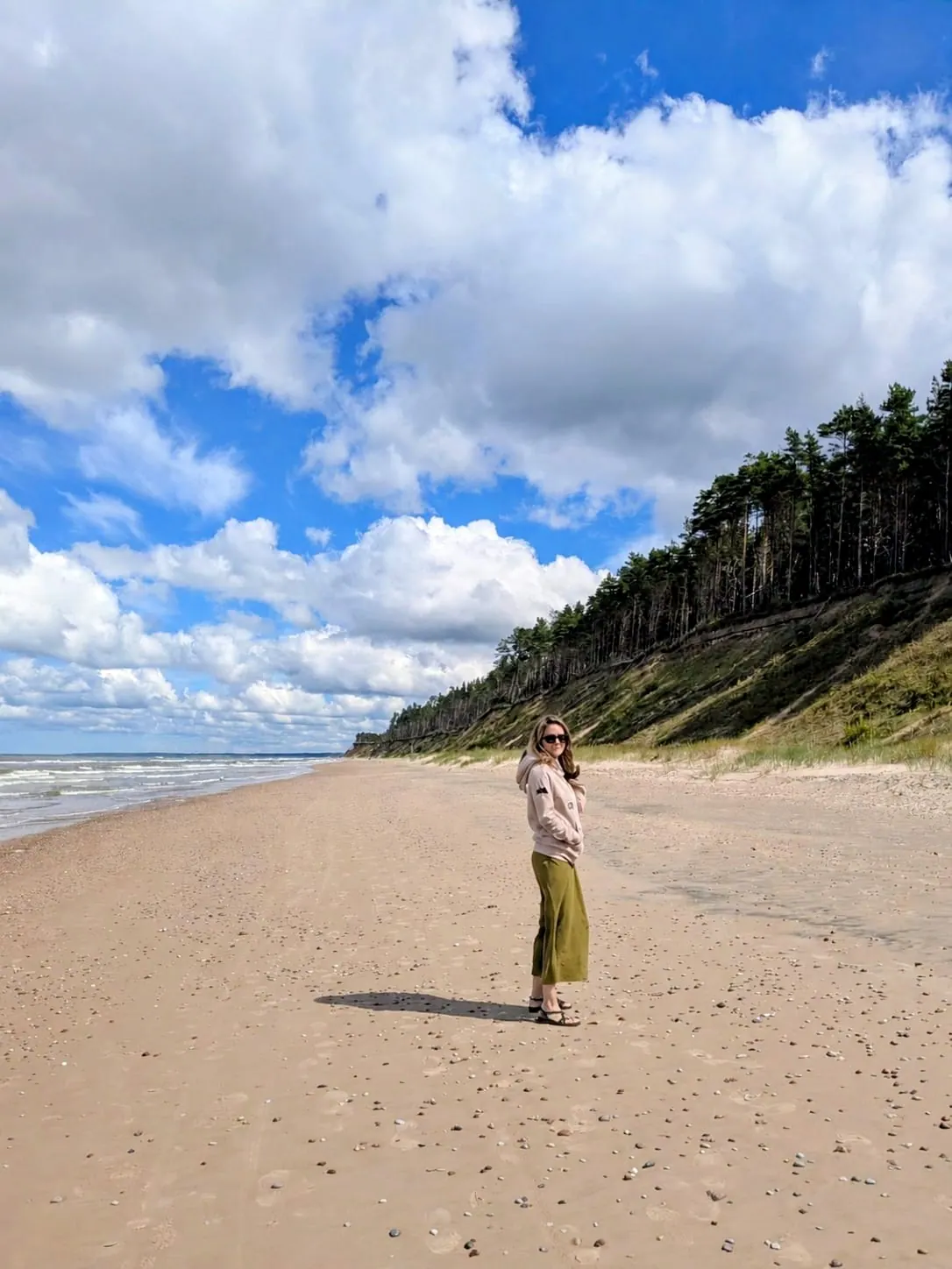A traveler walking beneath the high sandy banks on Jūrkalne beach