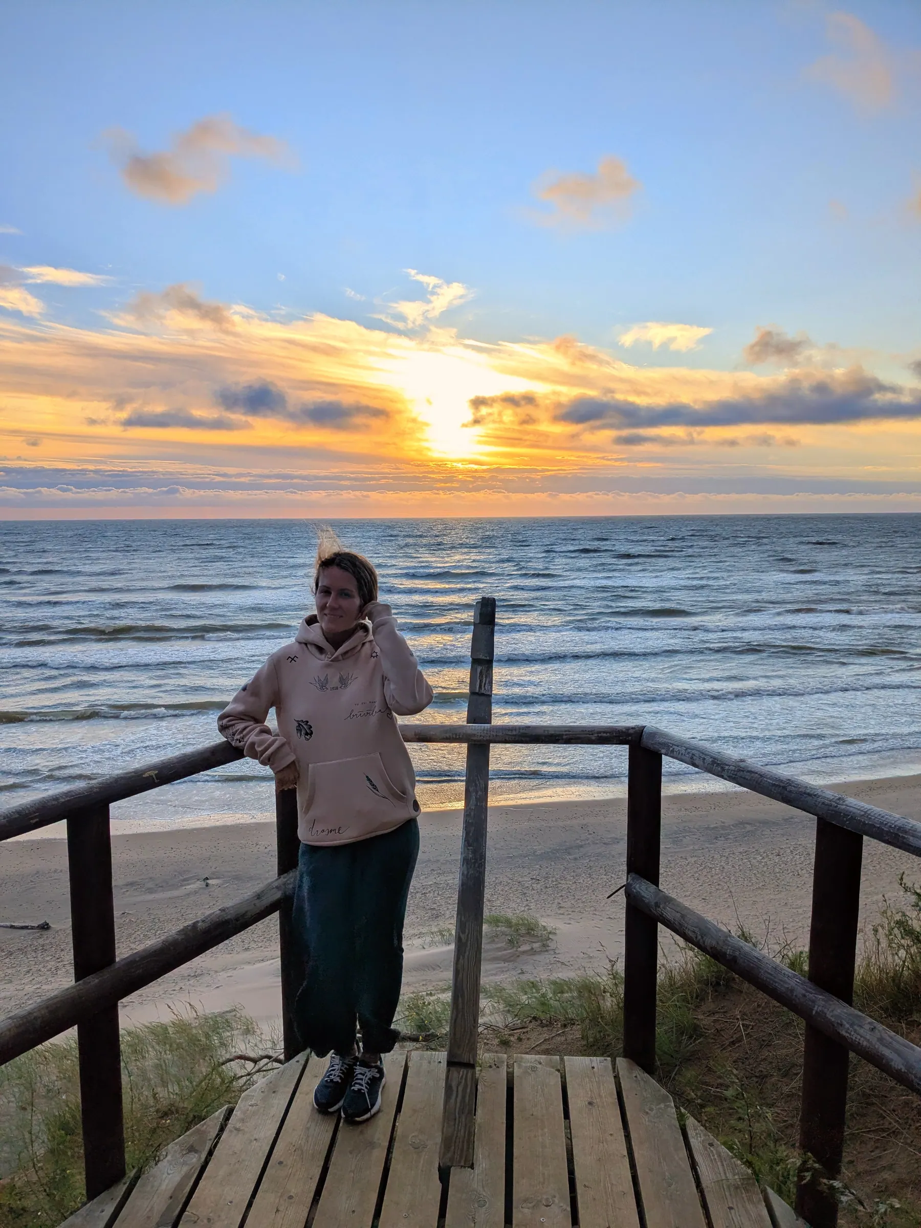 A traveler watching sunset from the clifftop platform at Jūrkalne
