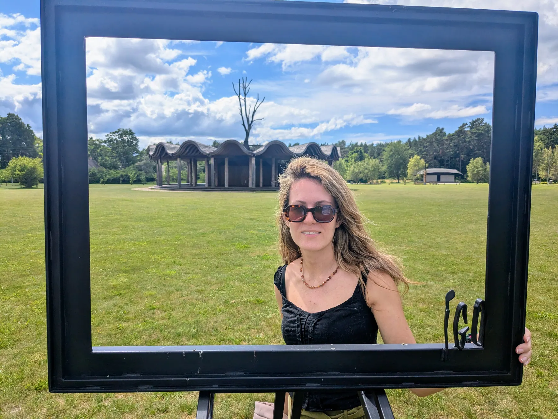 A traveler posing in an outdoor picture frame near Jūrkalne church