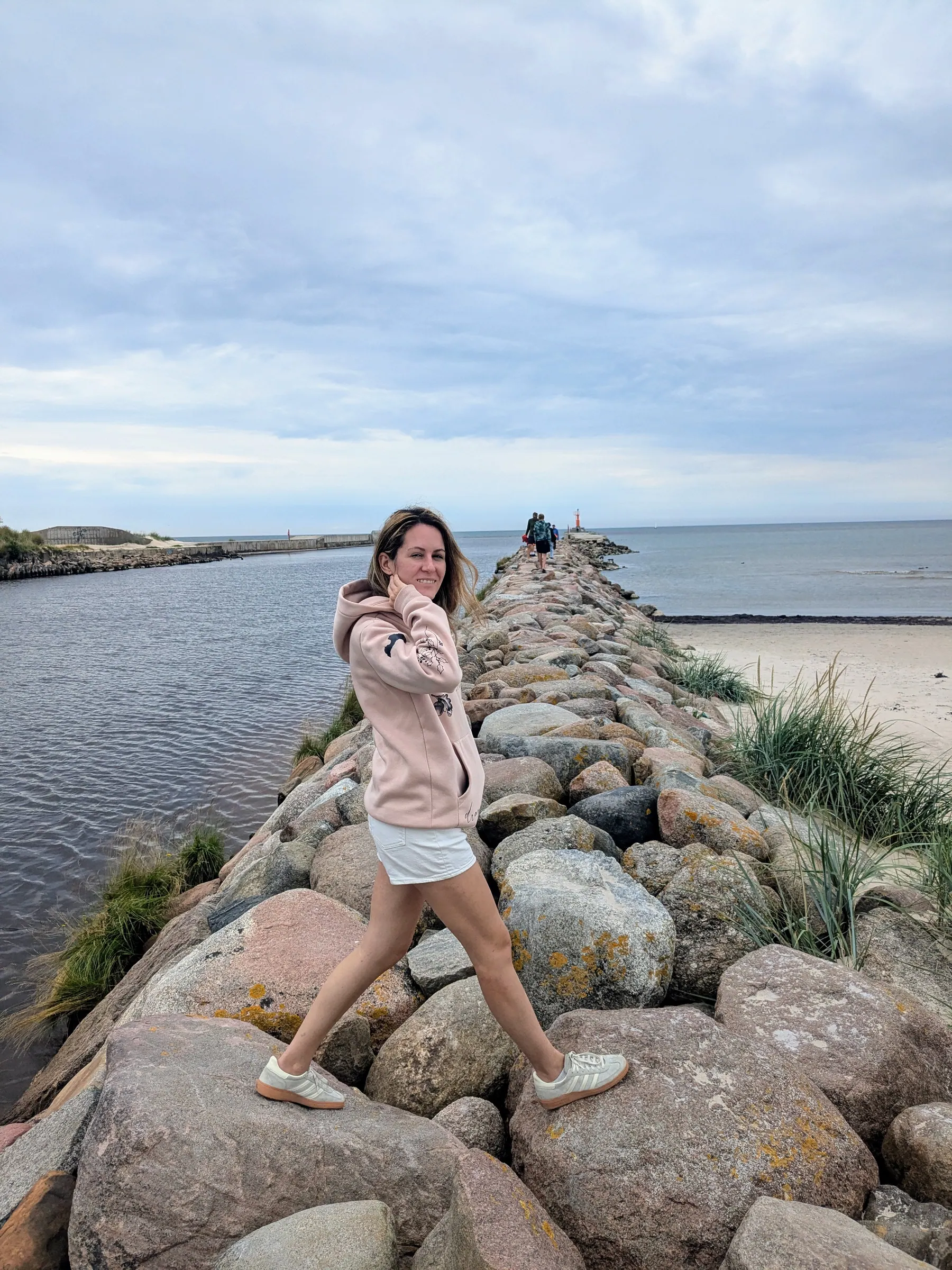 A traveler standing on the large rocks of Pāvilosta's harbour pier