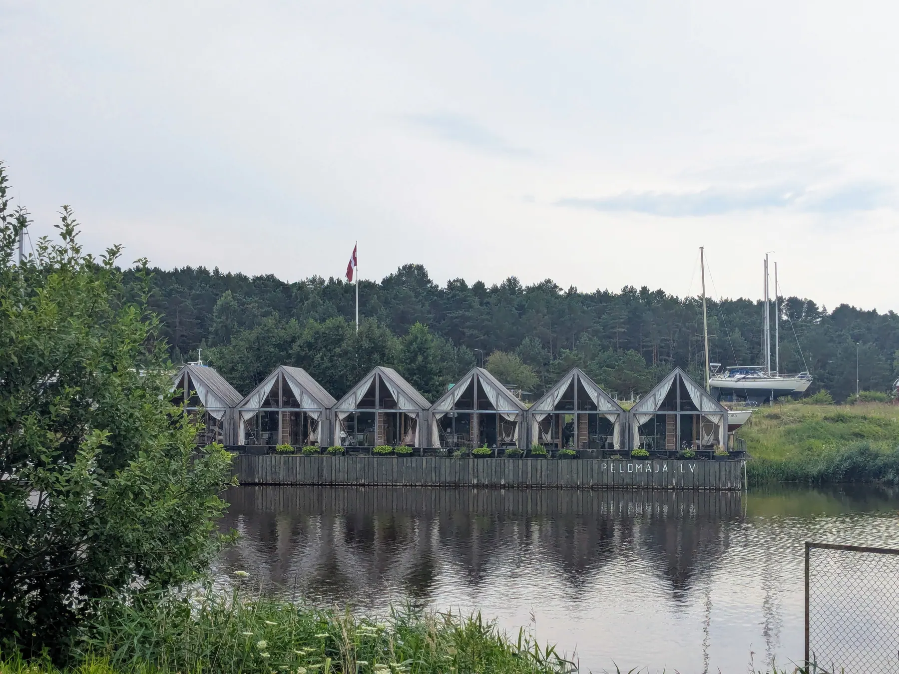 The Peldmāja floating cottages lined up on a pontoon on the Saka River