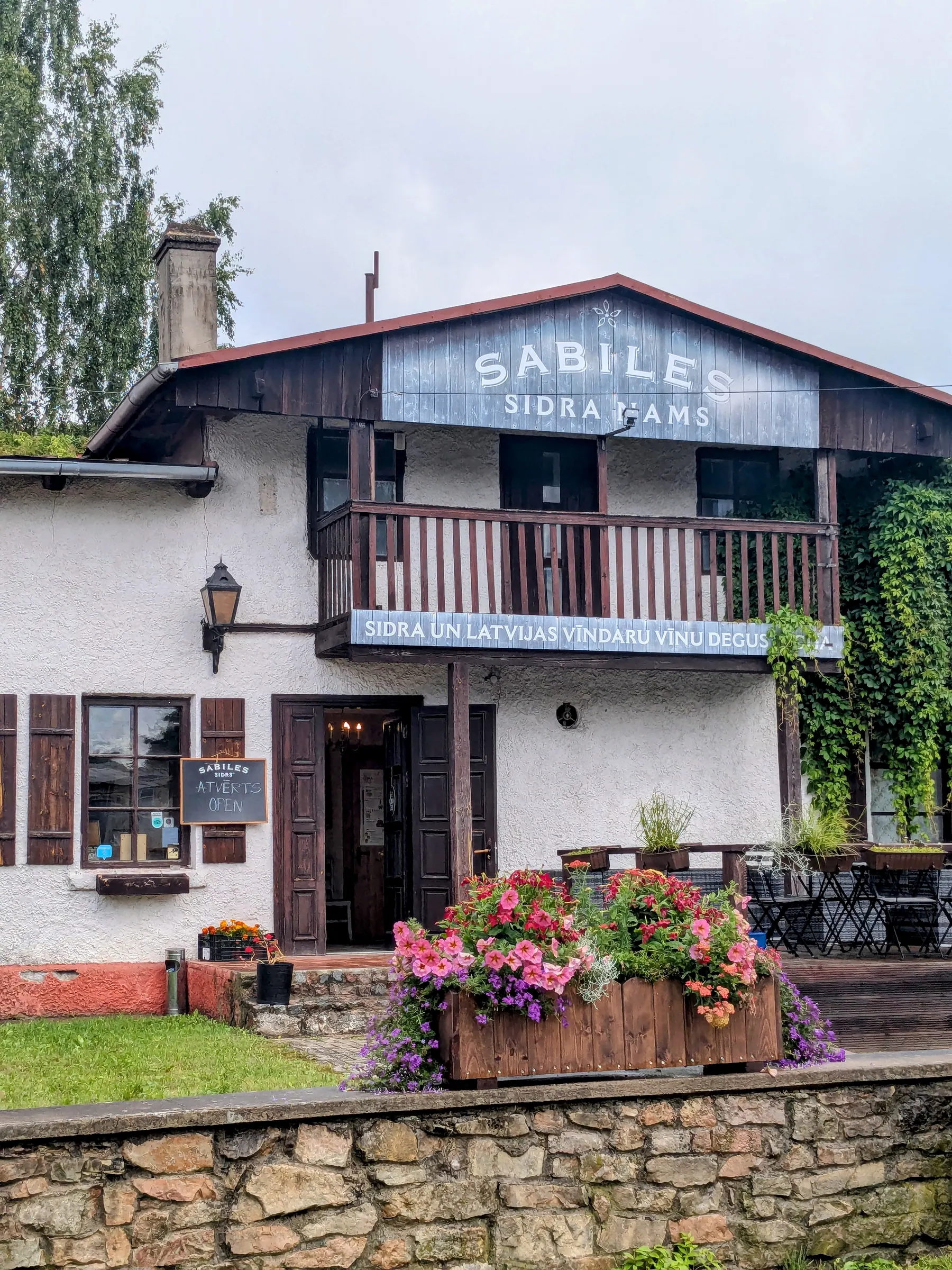 The flower-filled entrance of Sabiles Sidra Nams cider house