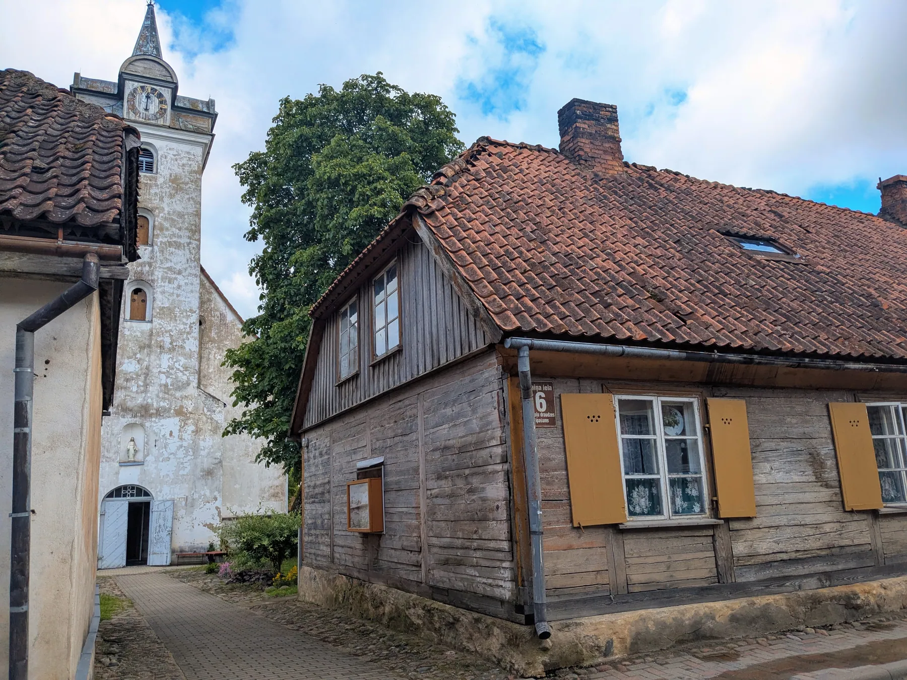 A historic wooden house and church tower in Kuldīga old town