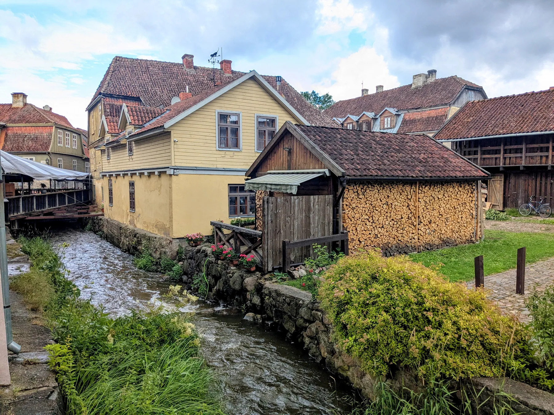 Aleksupīte flowing past wooden buildings in Kuldīga