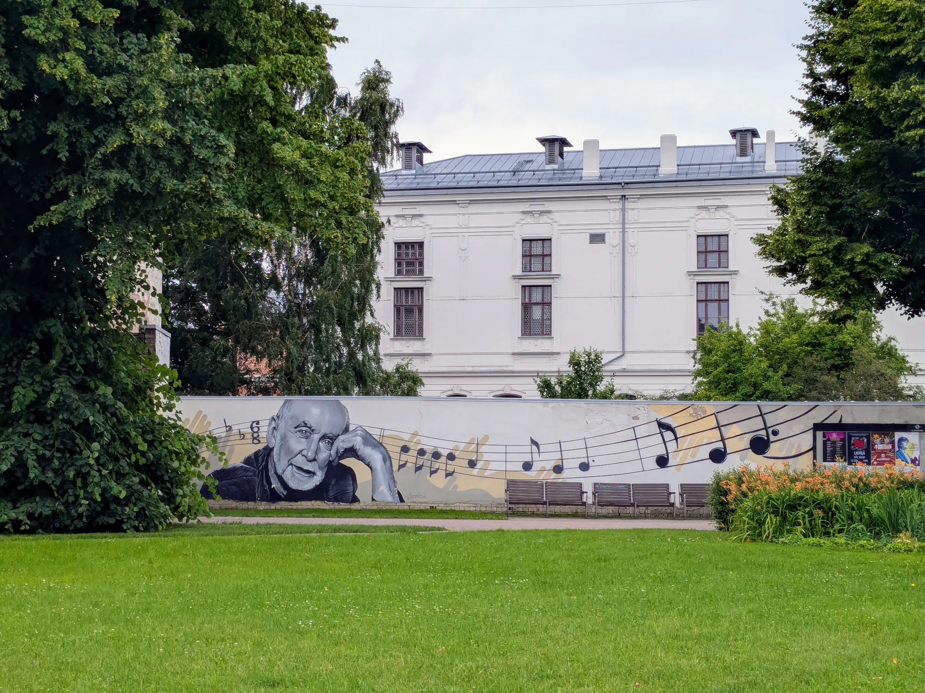 Un mural en blanco y negro con notas musicales junto a un jardín