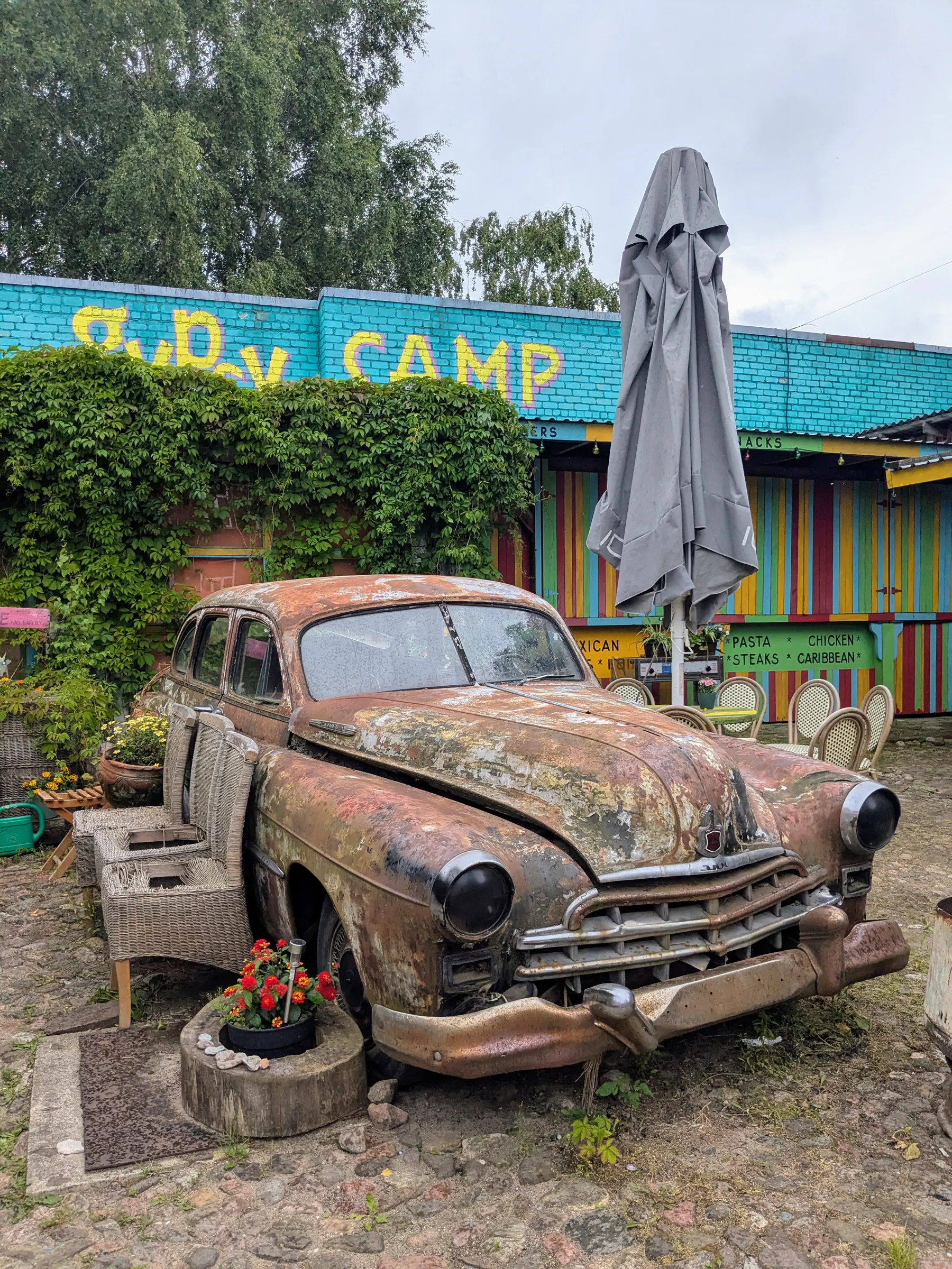 Un coche antiguo oxidado cubierto de plantas en el Gipsy Camp