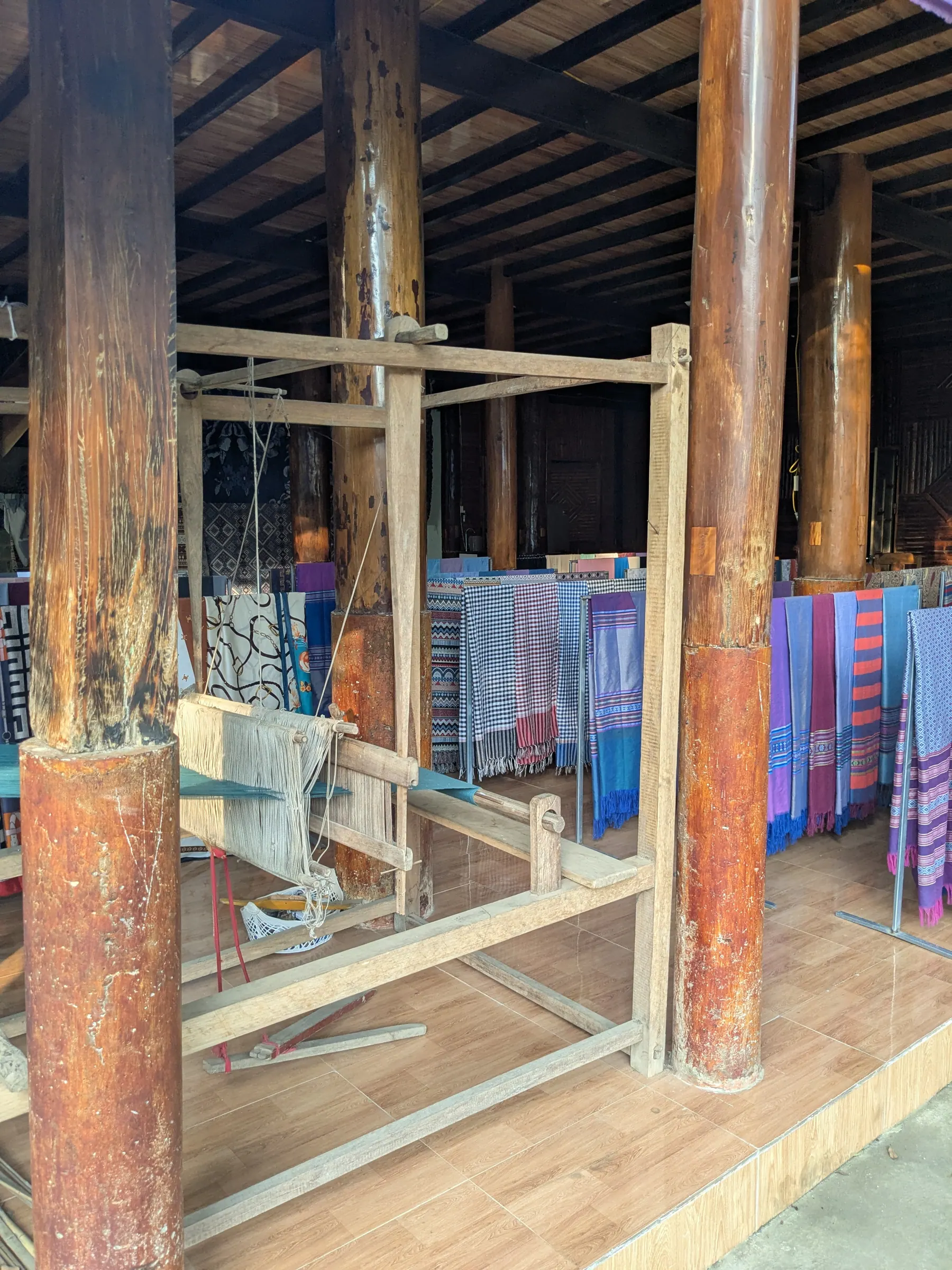 Colourful woven textiles displayed beside a wooden loom