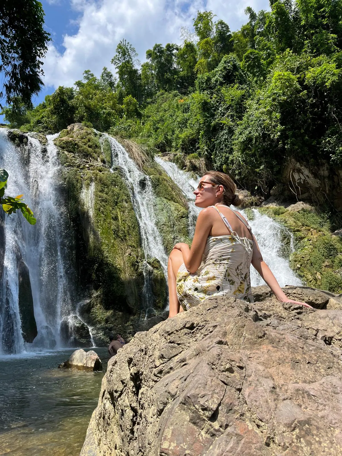 A traveller sitting on rocks beside Gò Lào waterfall