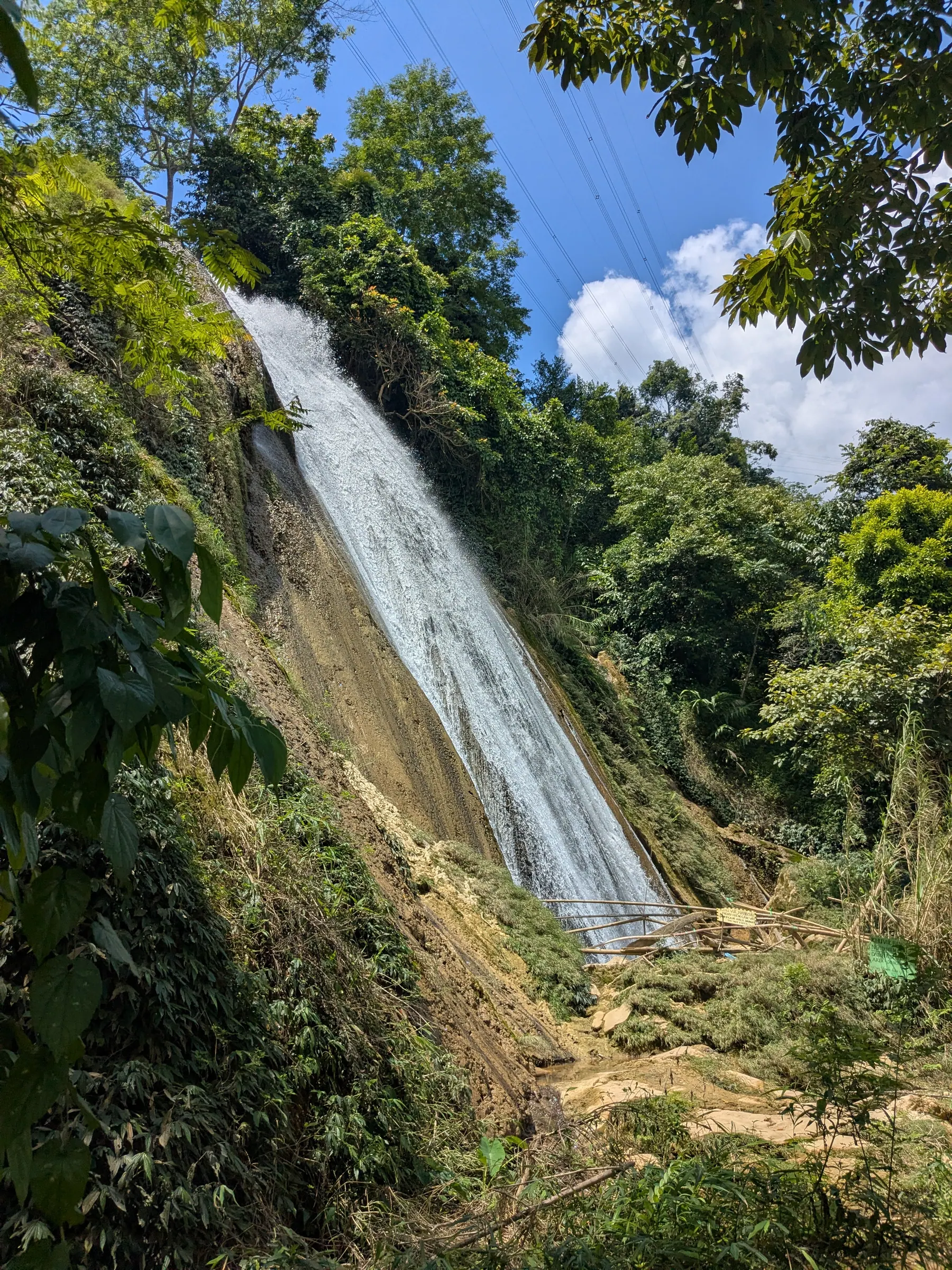 A tall waterfall flowing down a forested hillside
